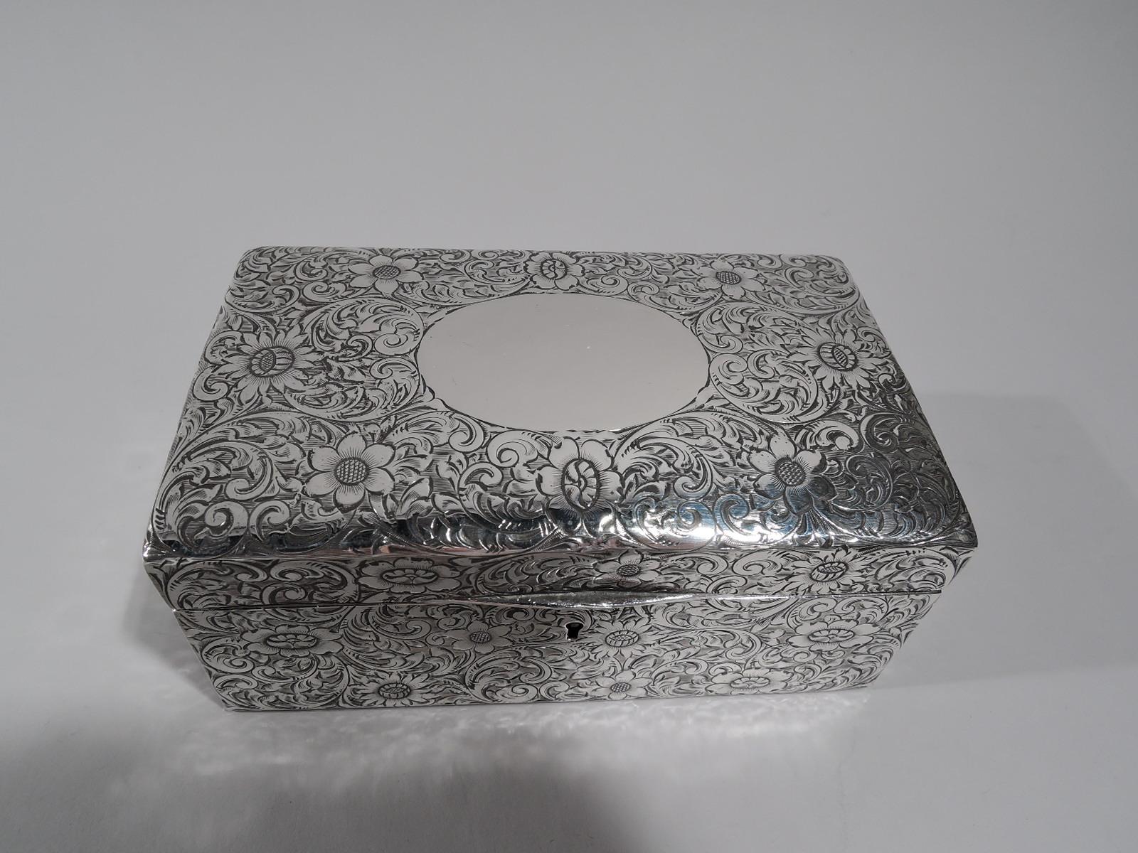 American Art Nouveau sterling silver jewelry box, circa 1910. Rectangular with straight sides. Cover hinged and gently curved with tapering tab. Dense scrolling flowers engraved all-over. Cover top has large oval frame (vacant). Box and cover velvet