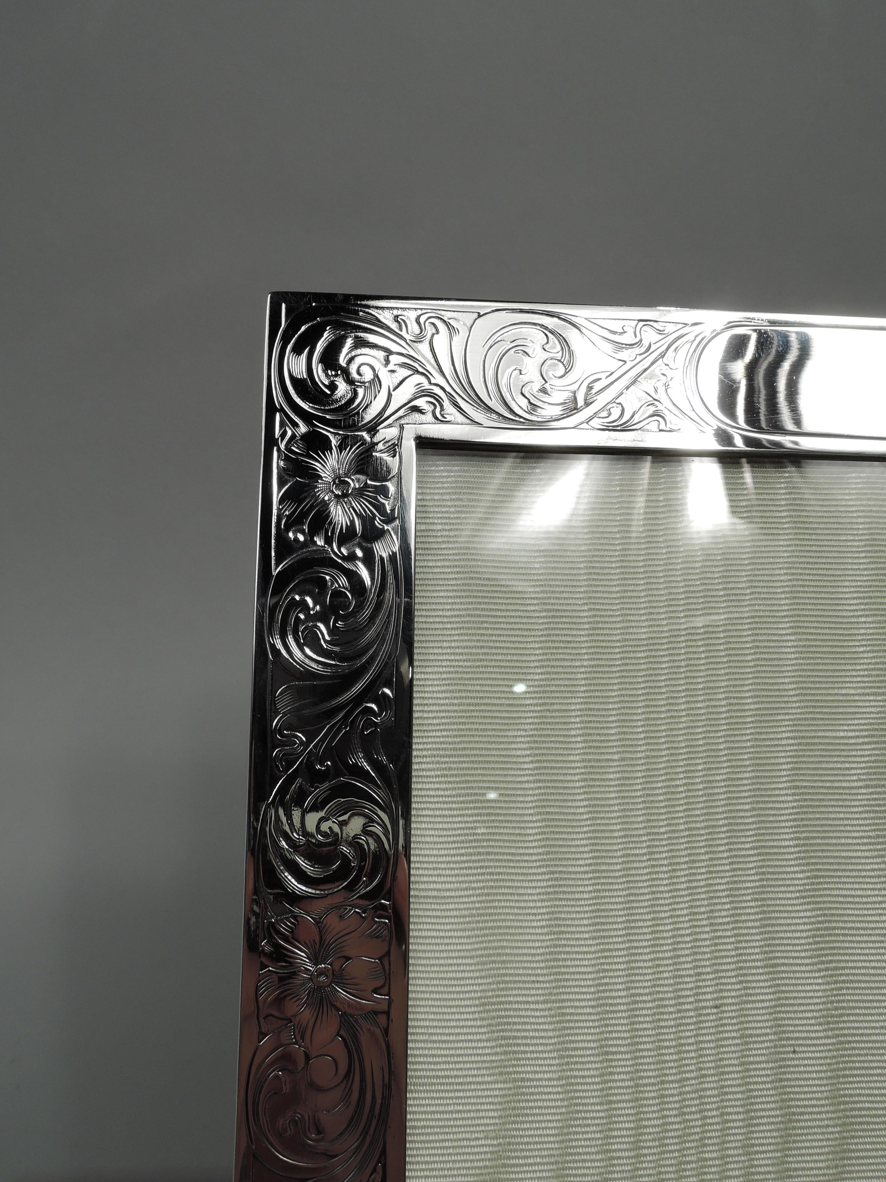 Art Nouveau sterling silver picture frame. Made by Mauser in New York, ca 1910. Rectangular window in flat surround with plain sides; front has acid-etched wraparound pattern with dense and fluid leafing scrolls and flower heads. Two corner ball