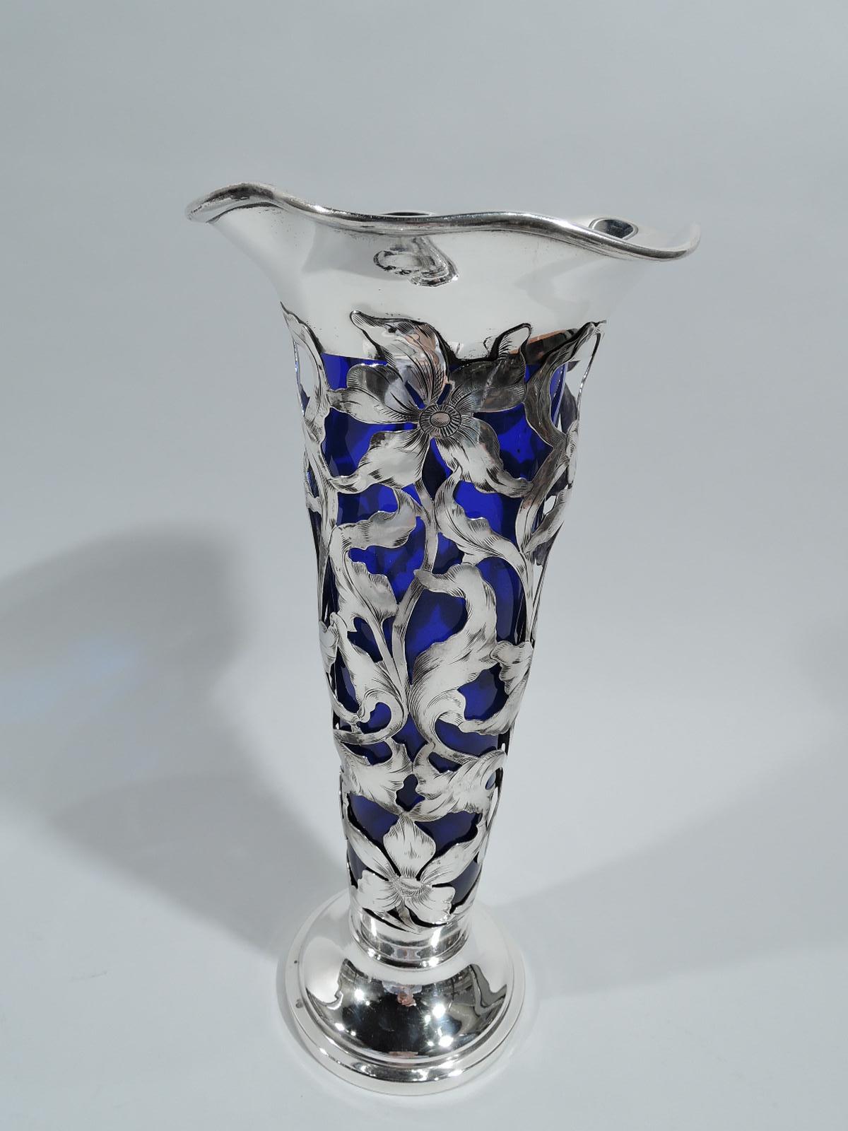 Art Nouveau sterling silver vase. Made by George A. Henckel & Co. in New York, ca 1910. Tapering open sides with engraved openwork in form of flowers and entwined and whiplash tendrils. Stapped and raised foot. Ruffled rim. Detachable cobalt glass