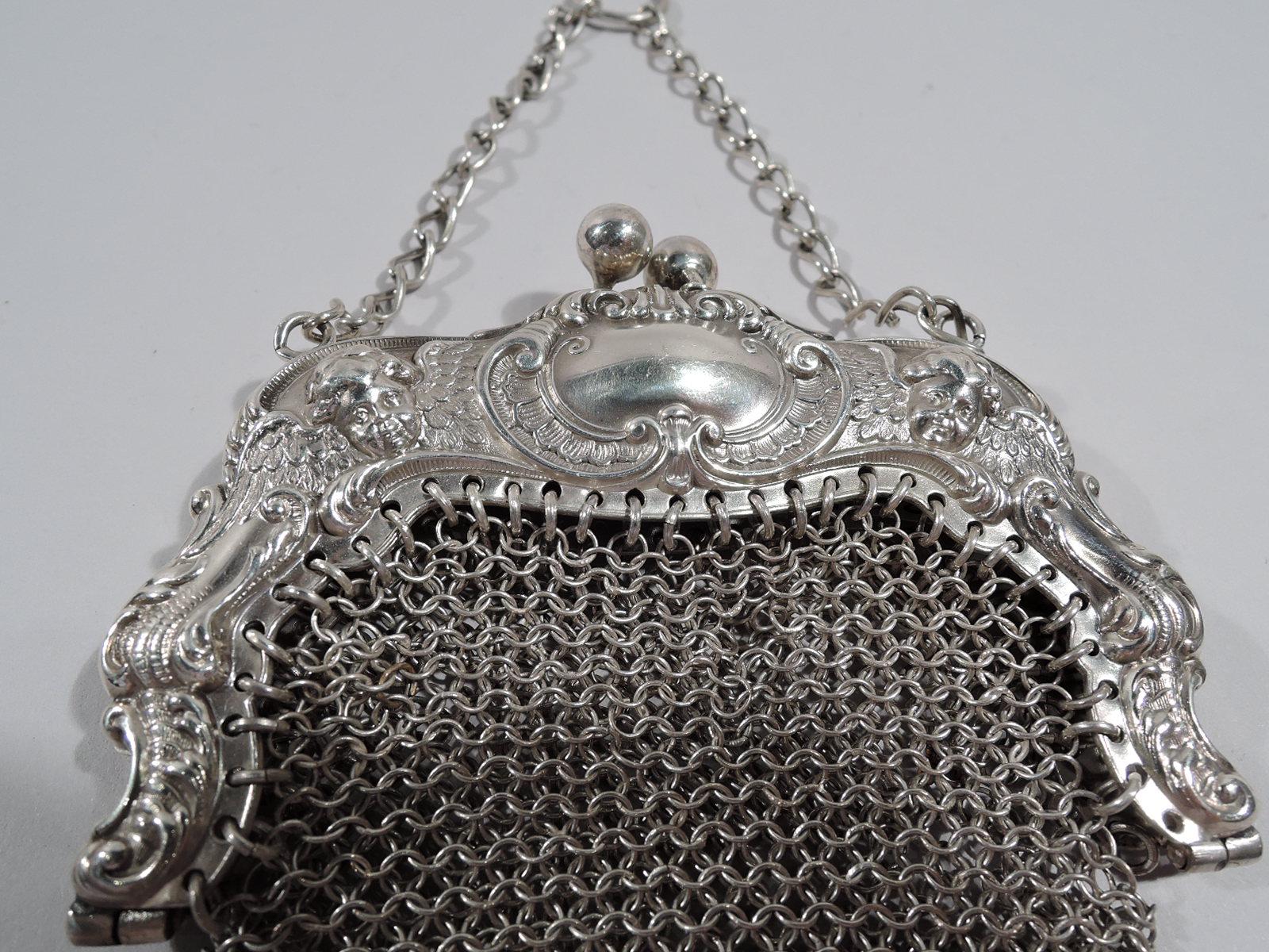 Amerikanische Jugendstil-Handgelenkstasche aus Sterlingsilber aus der Jahrhundertwende. Schnörkellose Klammeröffnung mit Puttenköpfen und Schnörkelkartuschen (eine mit eingraviertem Schriftmonogramm). Körper aus Kettengeflecht mit tropfenförmigen