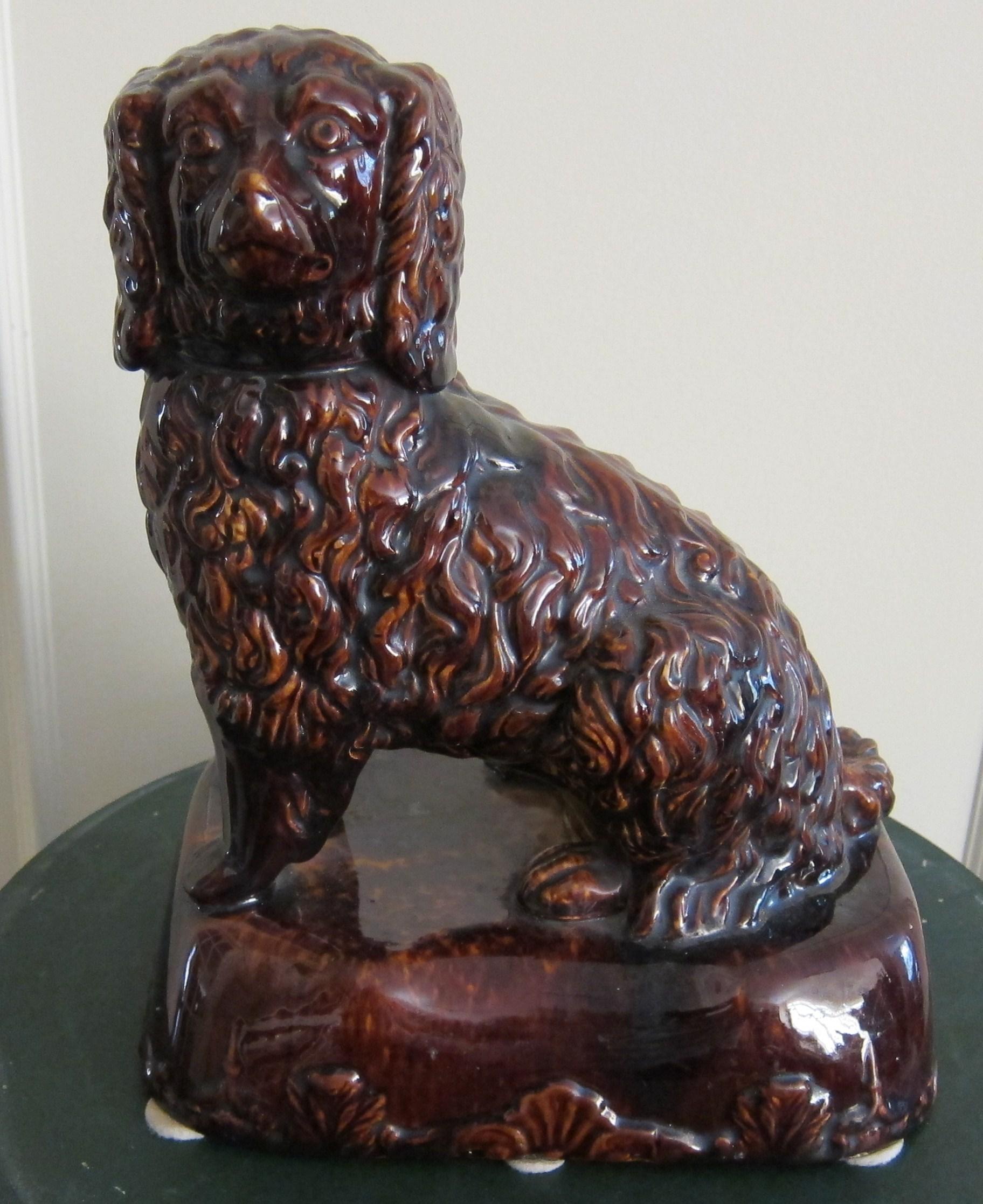 A brown treacle glaze figure of a seated Spaniel from the Bennington factory in Vermont USA.
 