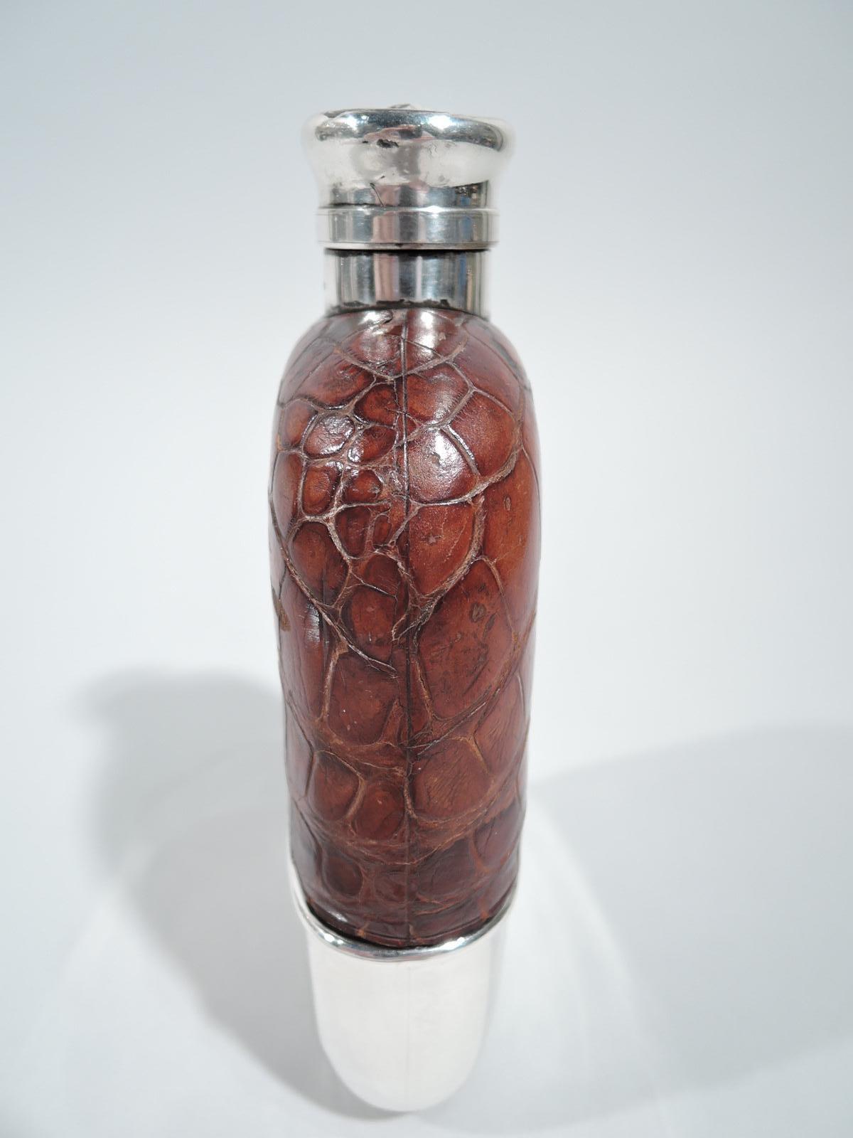 Big-game era flask. Made by Gorham in Providence in 1891. Clear-glass body. Top encased in leather and bottom has detachable sterling silver cup. Neck sterling silver as is hinged and cork-lined bayonet cover for convenient one-handed opening while