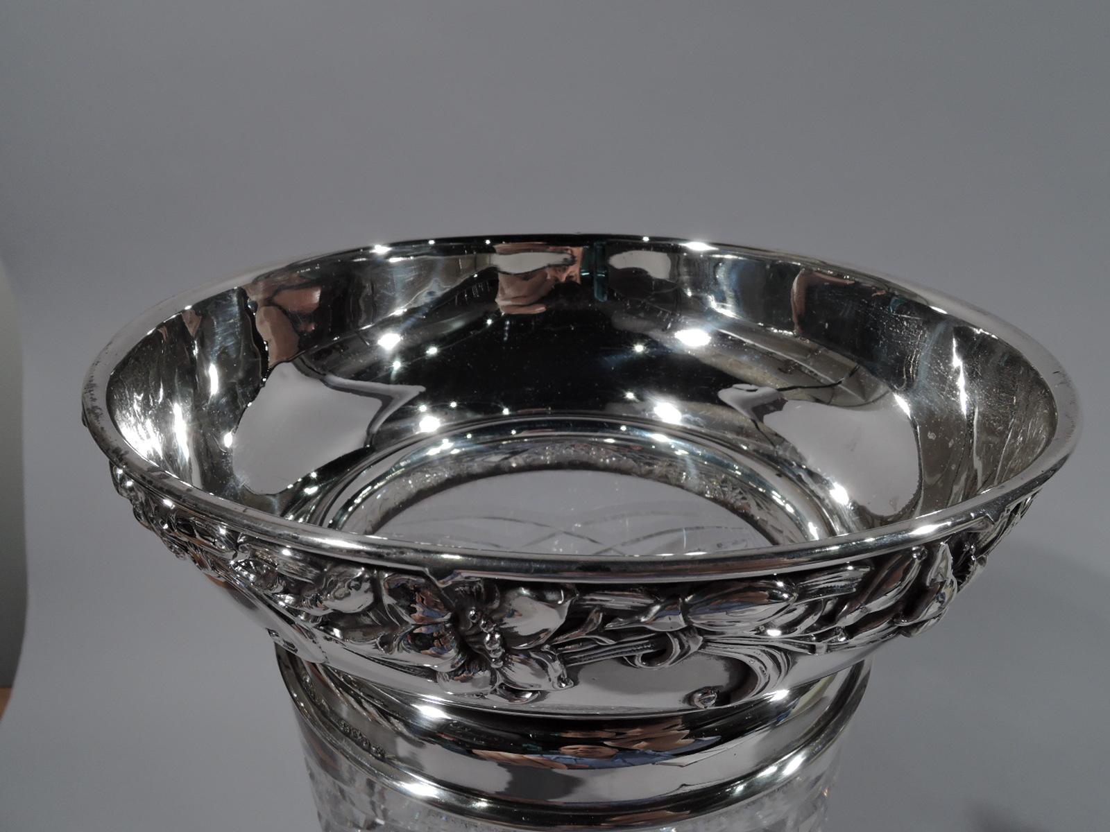 American brilliant-cut glass vase with sterling silver collar. Made by Gorham in Providence in 1907. Waisted cylinder with dense stars, ferns, and diaper ornament. Collar and curved and wide mouth applied with loose and entwined flowers. Fully