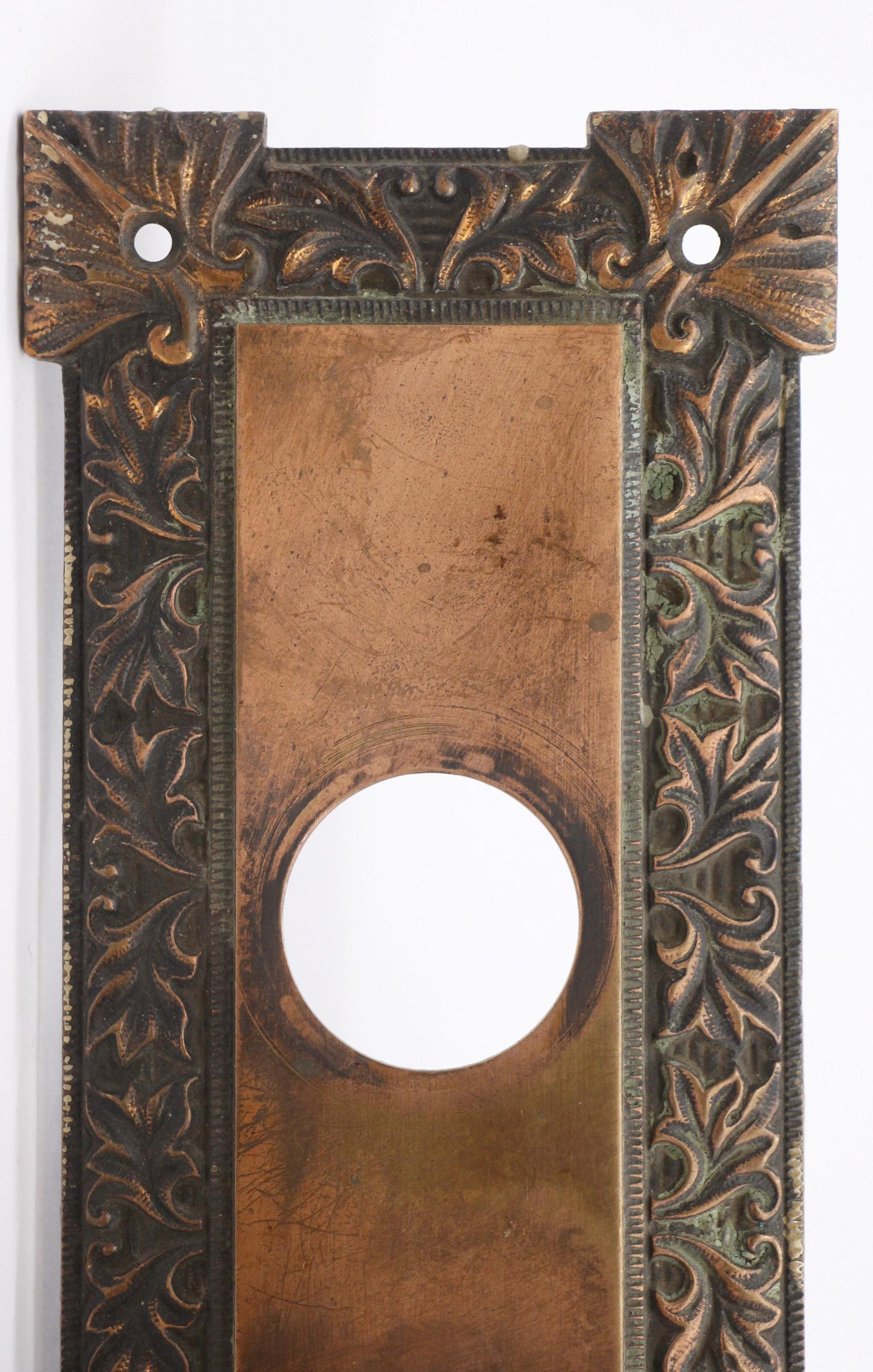 Cet ensemble de boutons de porte concentriques en bronze, datant du début du 20e siècle, fait partie du groupe M-One. L'ensemble comprend deux boutons avec une tige assortie, une plaque arrière extérieure avec une ouverture pour la serrure et une