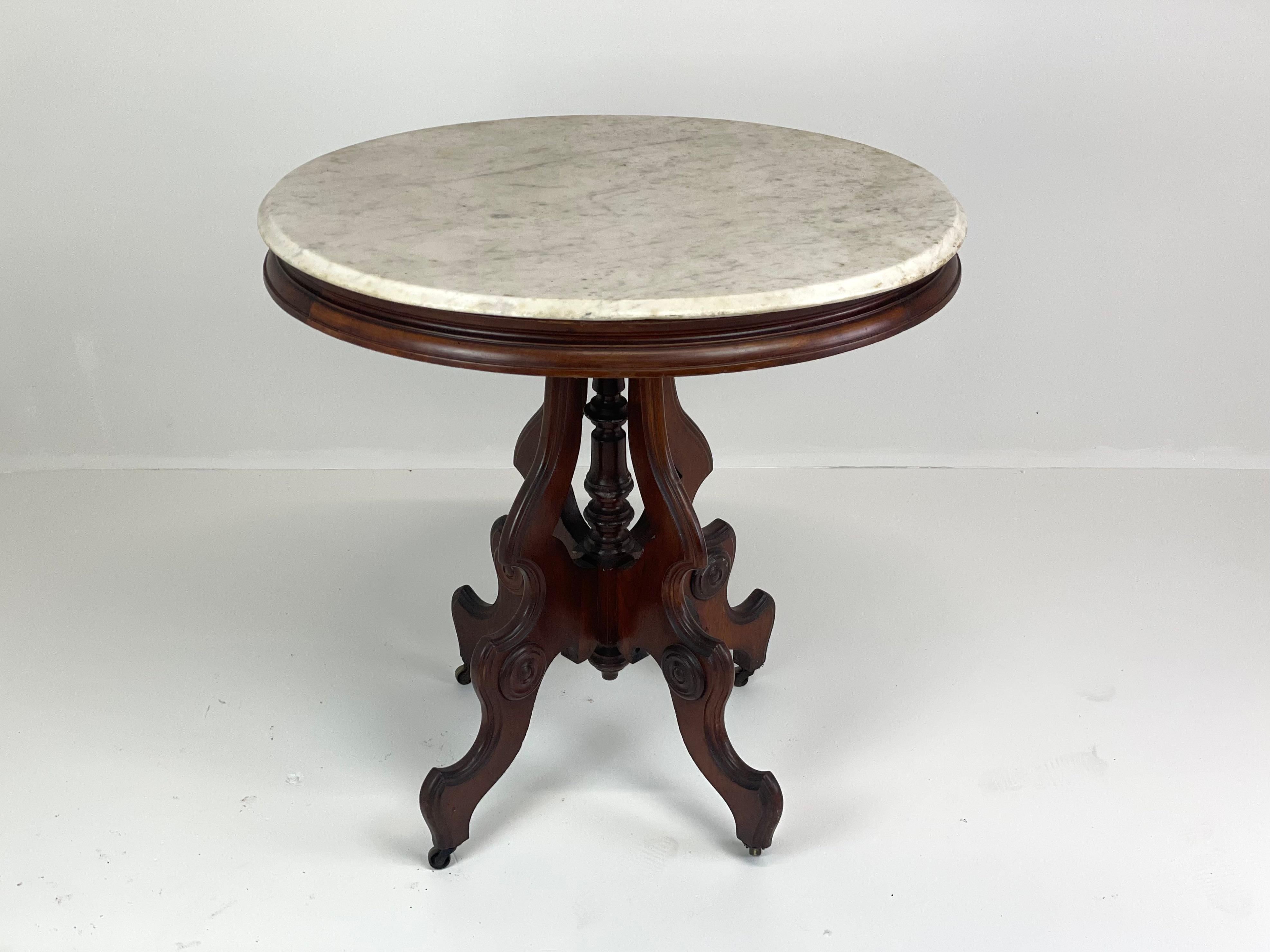 Table centrale américaine de style néo-rococo du milieu du 19e siècle. La table conserve son plateau d'origine en marbre blanc doucement patiné par le temps. La base en noyer est richement sculptée de pieds en volutes, de médaillons et d'un fleuron