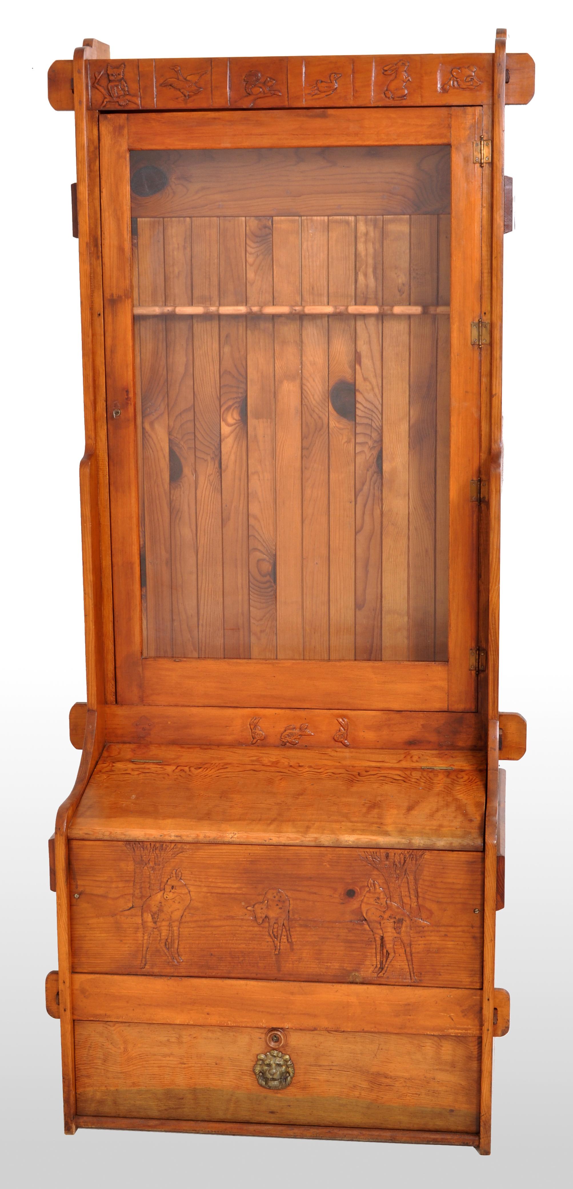 An unusual antique 'American Country' gun/rifle display cabinet, circa 1920. The cabinet made from knotty pine and having a single locking door with a glazed panel which encloses a rack for nine guns, above is a through mortise and tenon panel