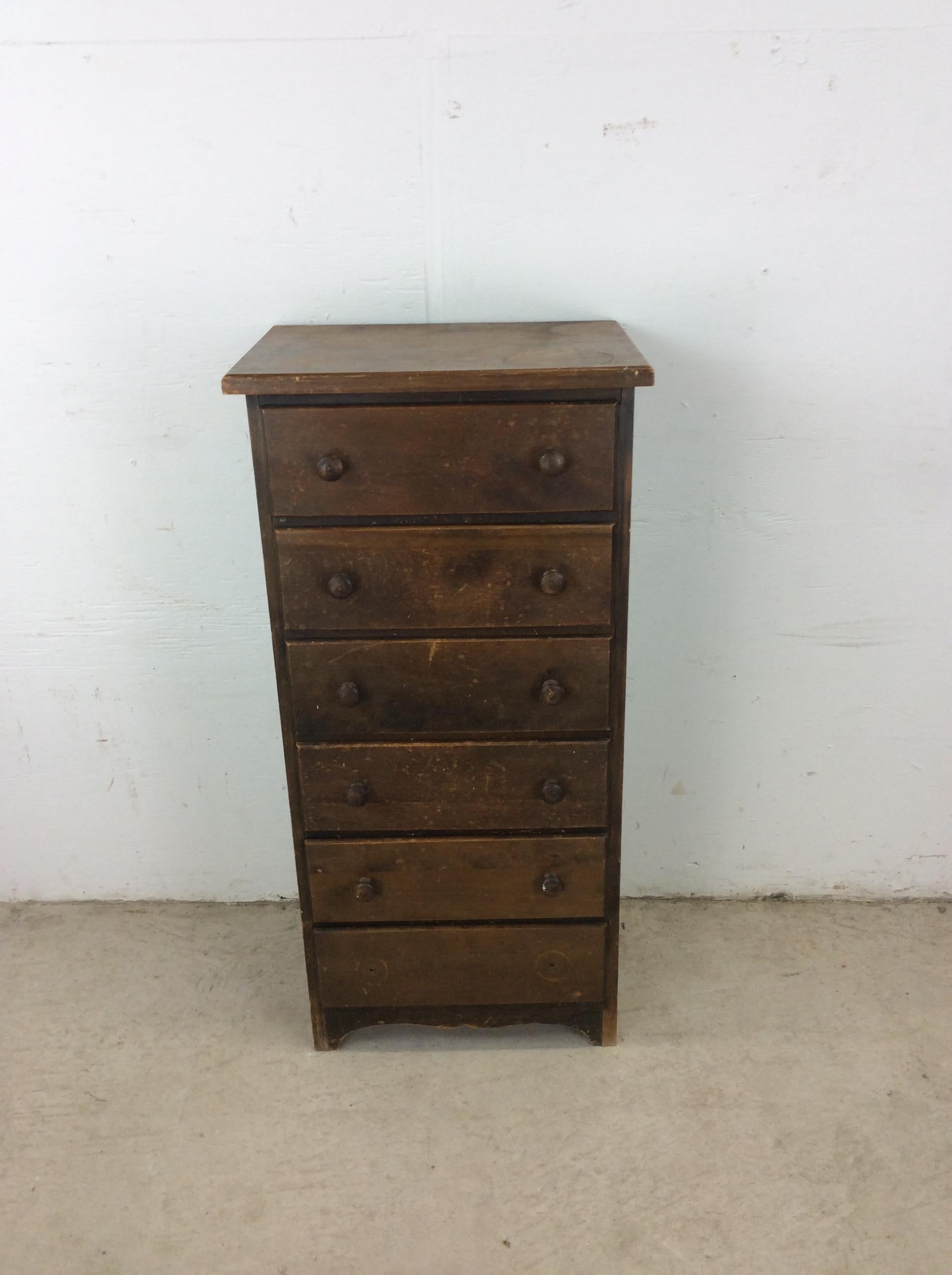 This antique chest of drawers features hardwood construction, original dark stain finish, six dovetailed drawers, and unique carved wood cabinet pulls.

Dimensions: 17.75w 13d 35.75h  

Condition notes: Original finish is weathered and stained. Top