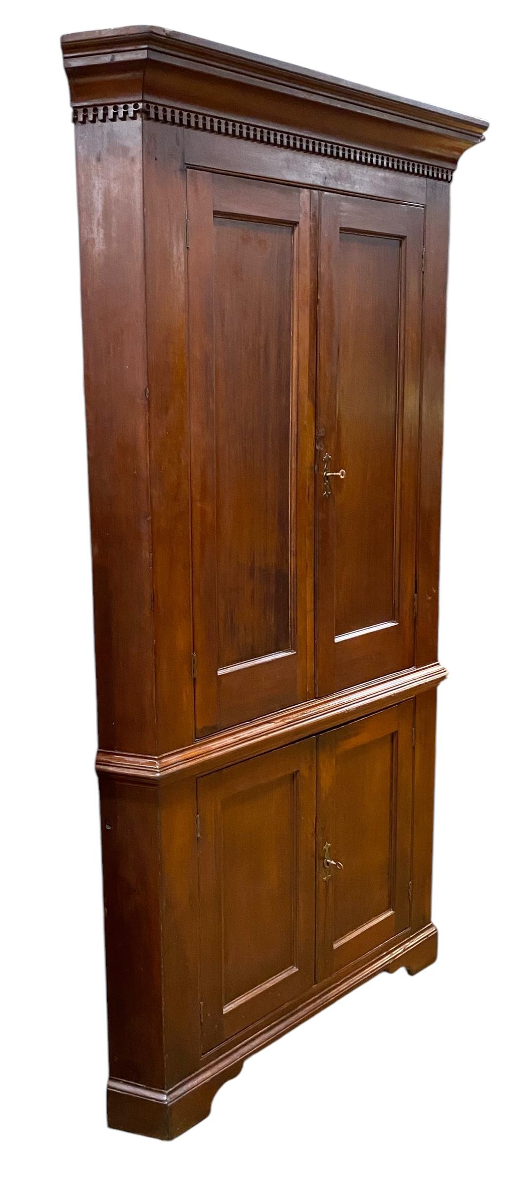 Antico armadio classico americano ad angolo in ciliegio, Pennsylvania, circa 1805
L'armadietto ha una cornice a gradini con modanatura a dentello sottostante, la parte superiore dell'armadietto ha due ante a doppio pannello che racchiudono tre