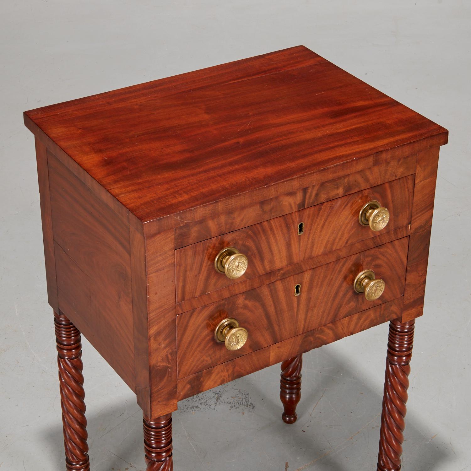 Early 19th c. American Classical figured mahogany nightstand on turned legs. Two flame mahogany drawers with embossed eagle brass pulls and keyholes (key not retained) below a convex bow front frieze.. The legs are beautifully turned with both spool