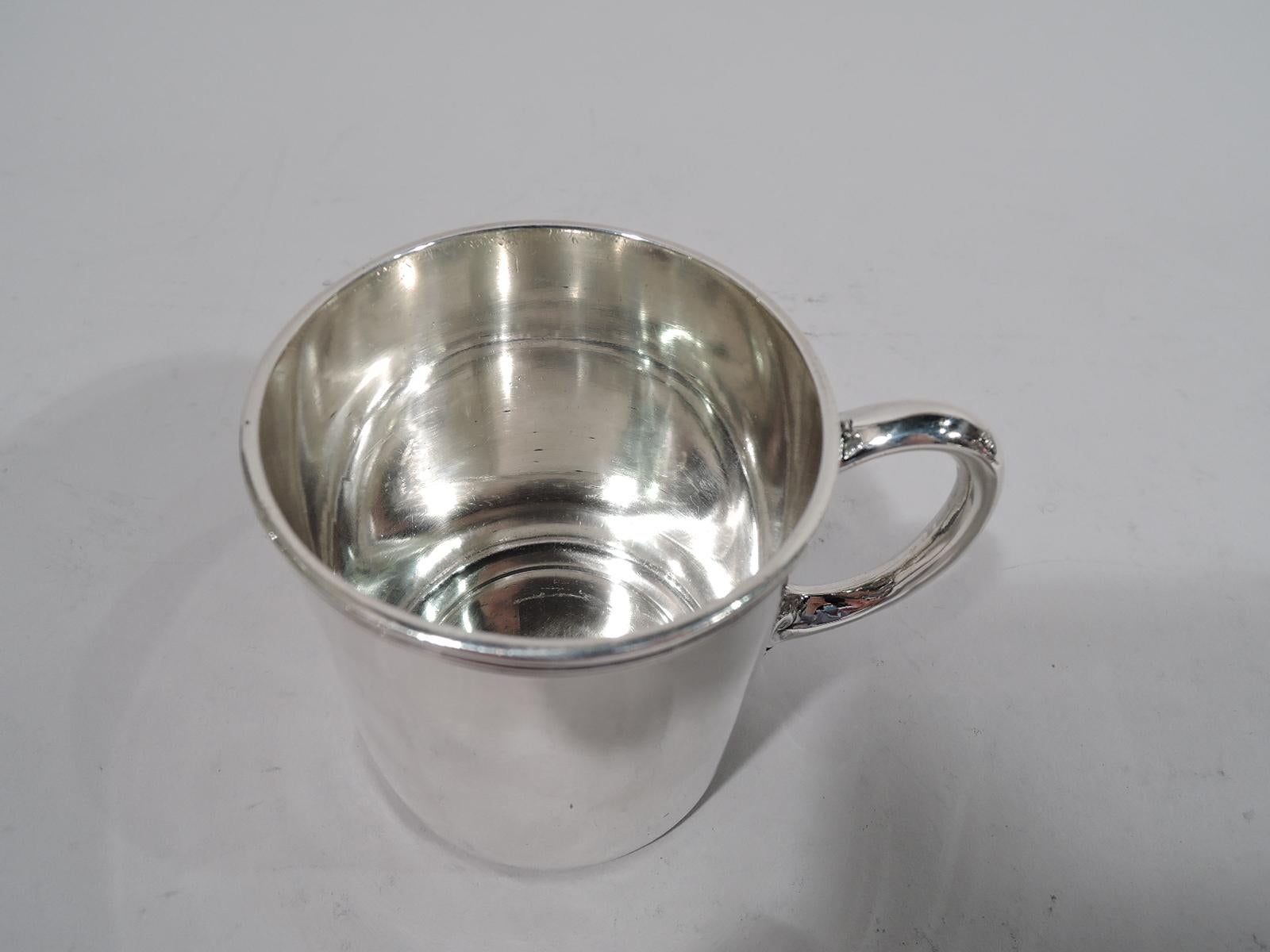 American classical sterling silver baby cup. Made by Tiffany & Co. in New York. Straight sides with curved bottom, reeded rim, and leaf-mounted C-scroll handle. Spare elegance with room for engraving. Fully marked including pattern no. 4105 and