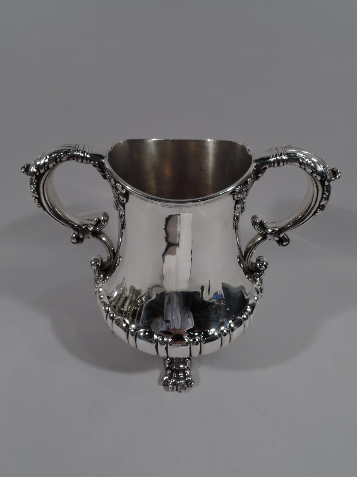 Turn-of-the-century classical sterling silver trophy cup. Made by Whiting in New York. Bellied urn with bold stylized egg-and-dart border on foot ring with four leaf-mounted majorly big paws. Leaf-capped and mounted S-scroll side handles. Beautiful