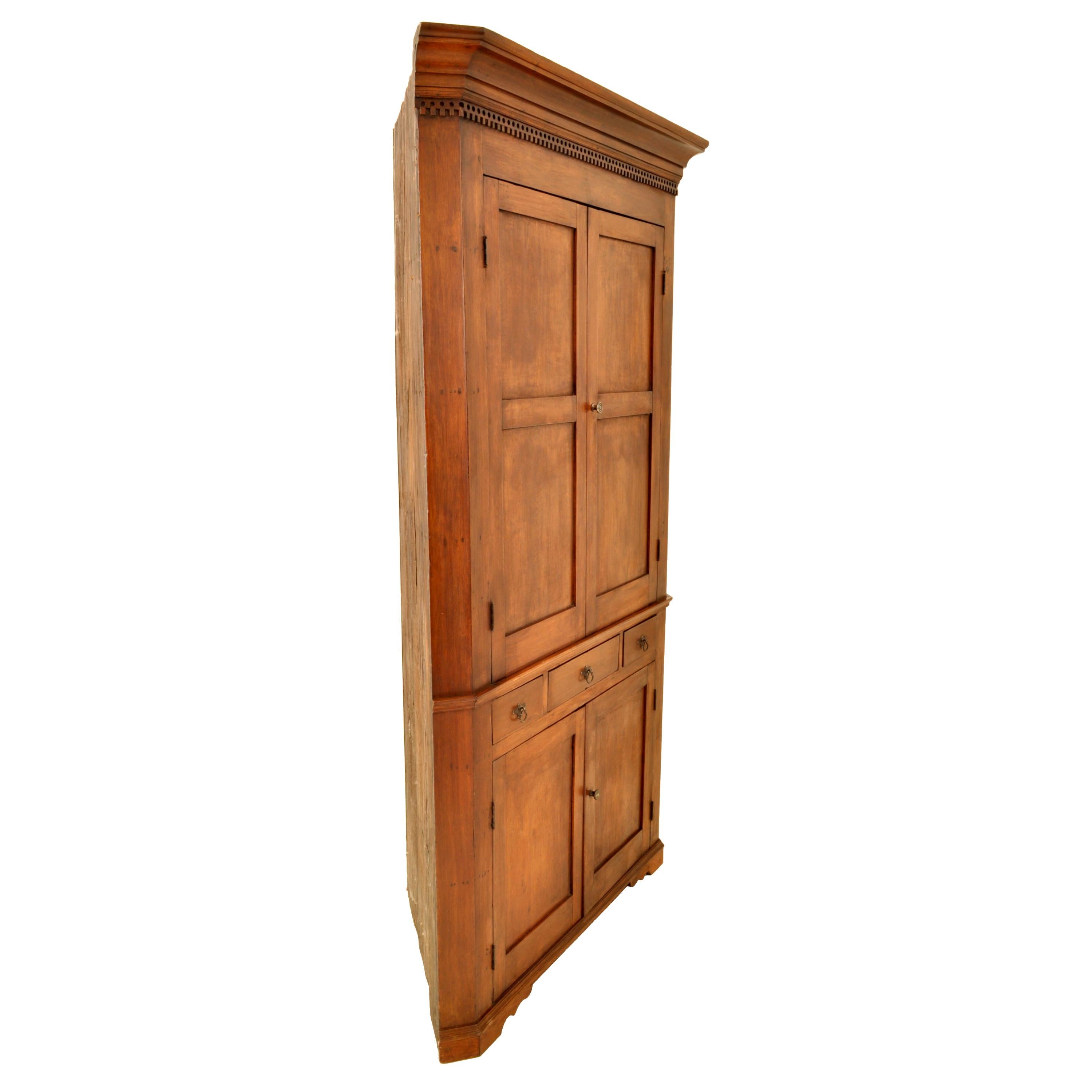 Antique American Colonial cherry corner cabinet, Pennsylvania, circa 1830.
The cabinet having a stepped cornice with dentil molding below, the top part of the cabinet having twin paneled doors, enclosing three shelves, the doors having traces of the