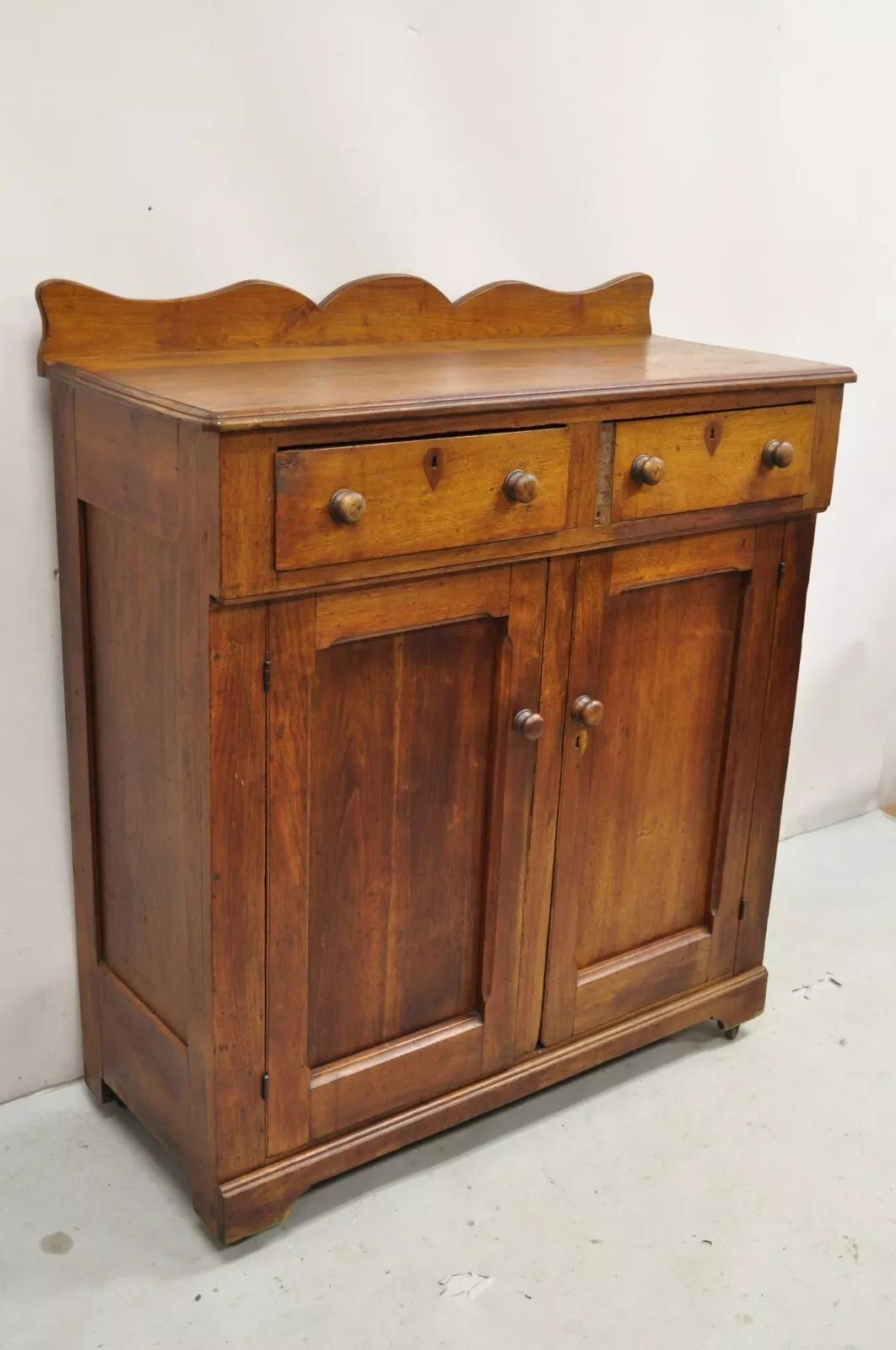 Antiguo Armario Colonial Americano Primitivo de Caoba con 2 Cajones. El artículo tiene un salpicadero tallado, 2 cajones hechos a mano con cola de milano, 2 puertas batientes, ruedas rodantes, hermosas vetas de madera, un armario antiguo muy bonito.