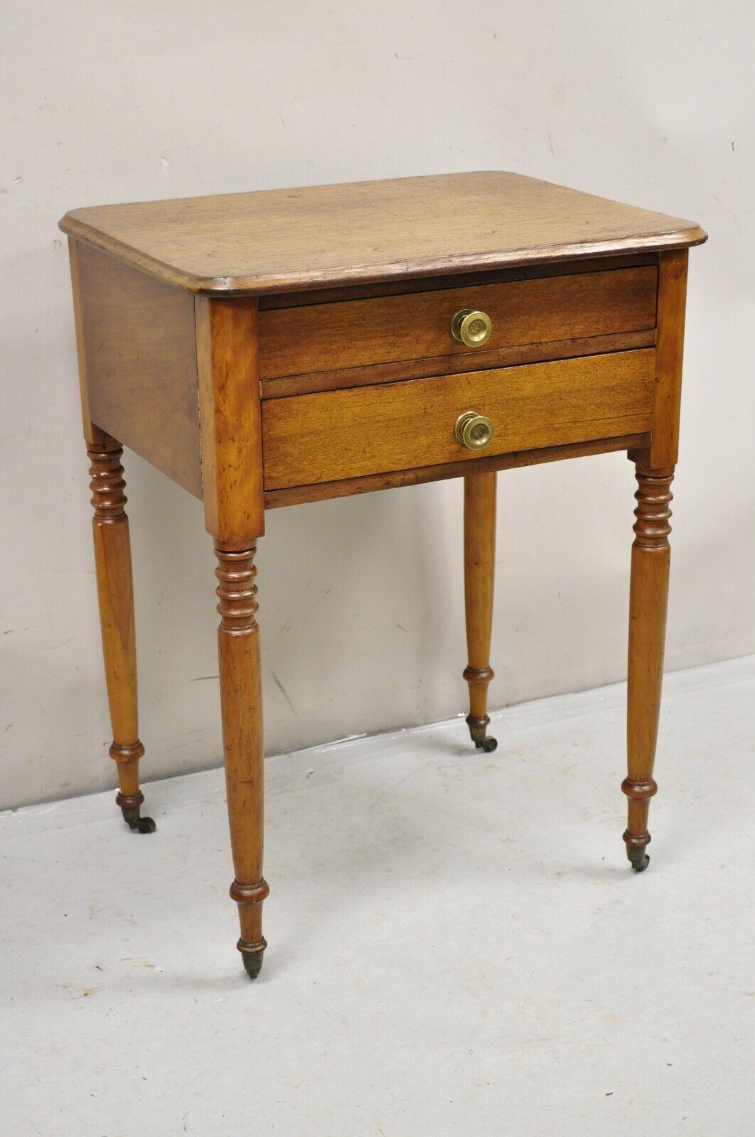 Antique American Colonial Sheraton Mahogany 2 Drawer Nightstand Bedside Table. Item featured has 2 hand dovetailed drawers, brass hardware, turned carved legs, brass rolling casters, beautiful wood grain, very nice antique item. Circa Mid 1800s
