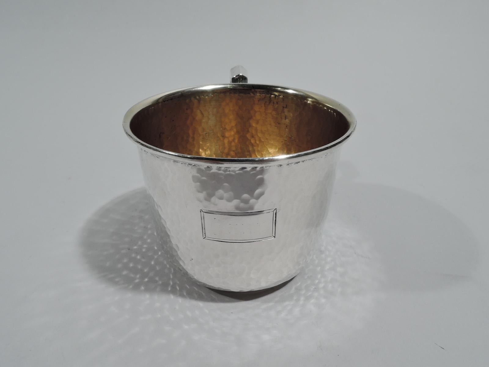 Craftsman sterling silver baby cup. Made by Watrous (part of International) in Wallingford, Conn., ca 1920. Straight sides with inset foot ring and scroll bracket handle. Allover hand hammering and plain rectangular cartouche (vacant). Gilt