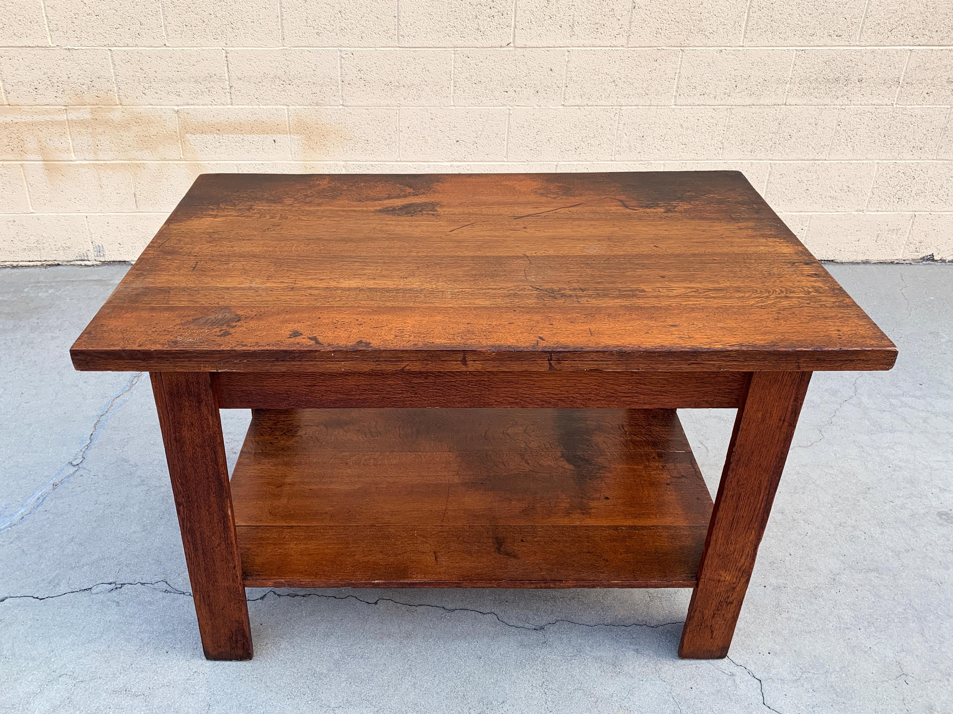 Beautifully made antique oak library table, circa 1920s American craftsman period. Constructed of solid oak with quarter sewn oak plank shelf and 2