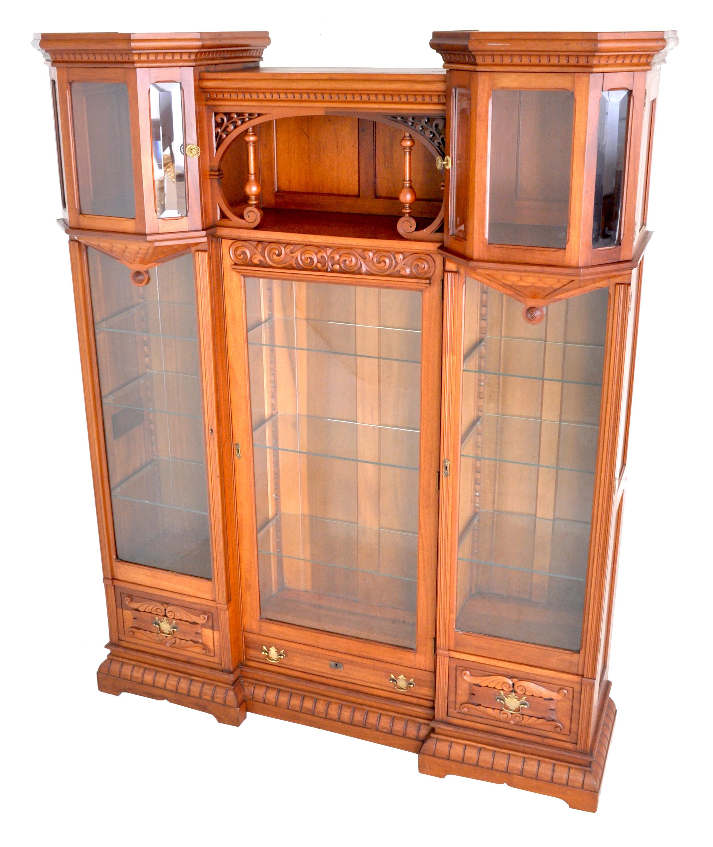 Antique American Eastlake walnut breakfront bookcase/hutch/cabinet, circa 1890. To the center is an area with pierced brackets and turned supports flanked by two turret style doors with beveled glass, the turrets having dentil molding to the top and