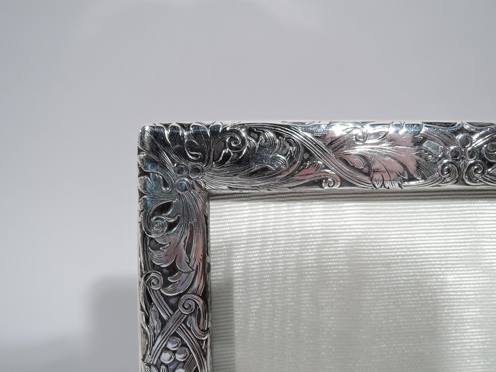 Edwardian Art Nouveau sterling silver picture frame. Made by William B. Kerr in Newark, circa 1910. Rectangular window in surround with acid-etched ornament: Leaves and berries threaded through and entwined with double scrolling bands. Rectangular