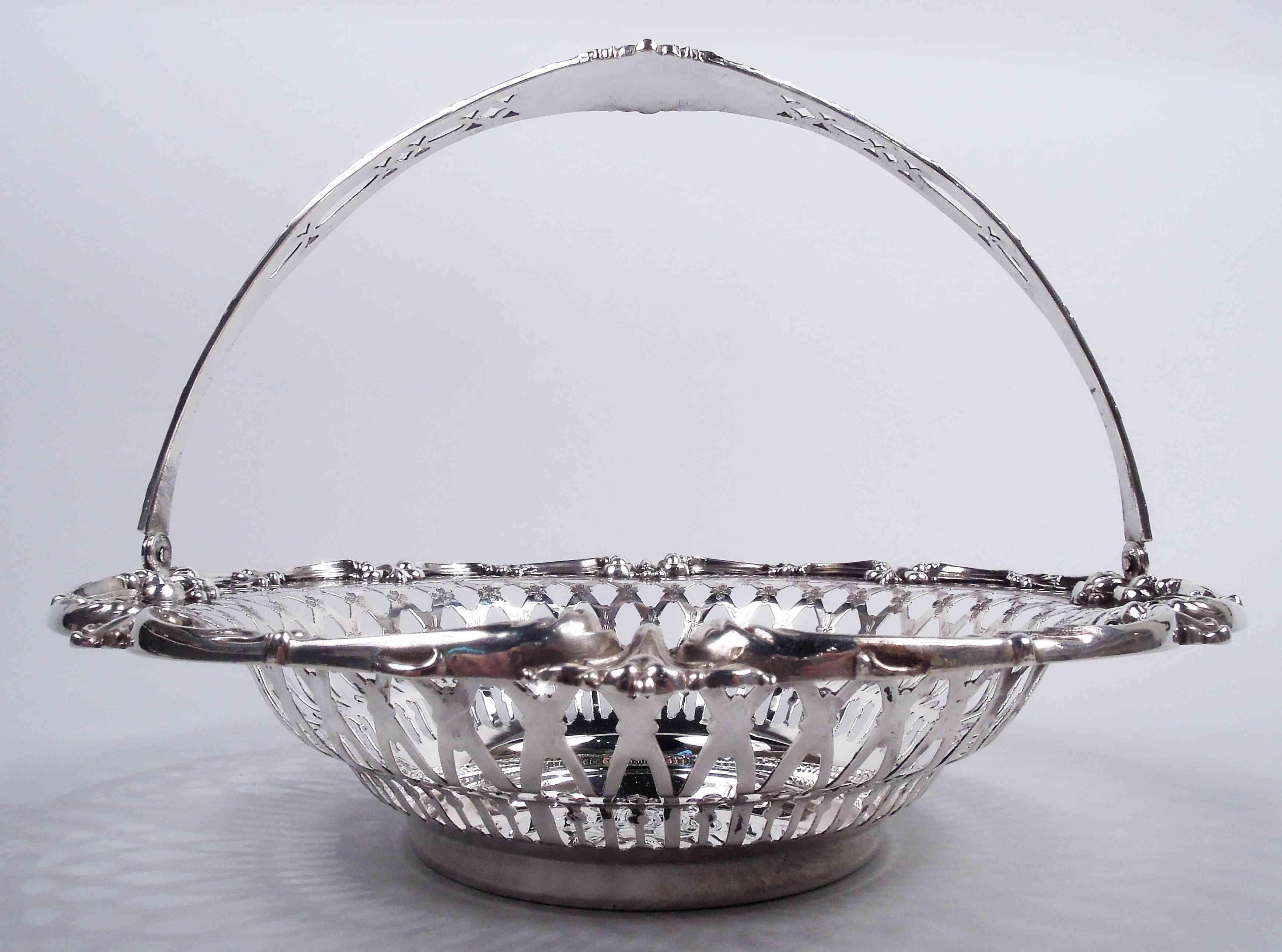 American Edwardian Classical sterling silver basket, ca 1910, Solid well engraved with interlaced script monogram. Sides and shoulder pierced with colonnade, arcade, diaper, and fleurs de lys. Rim has applied leafing scrolls interspersed with