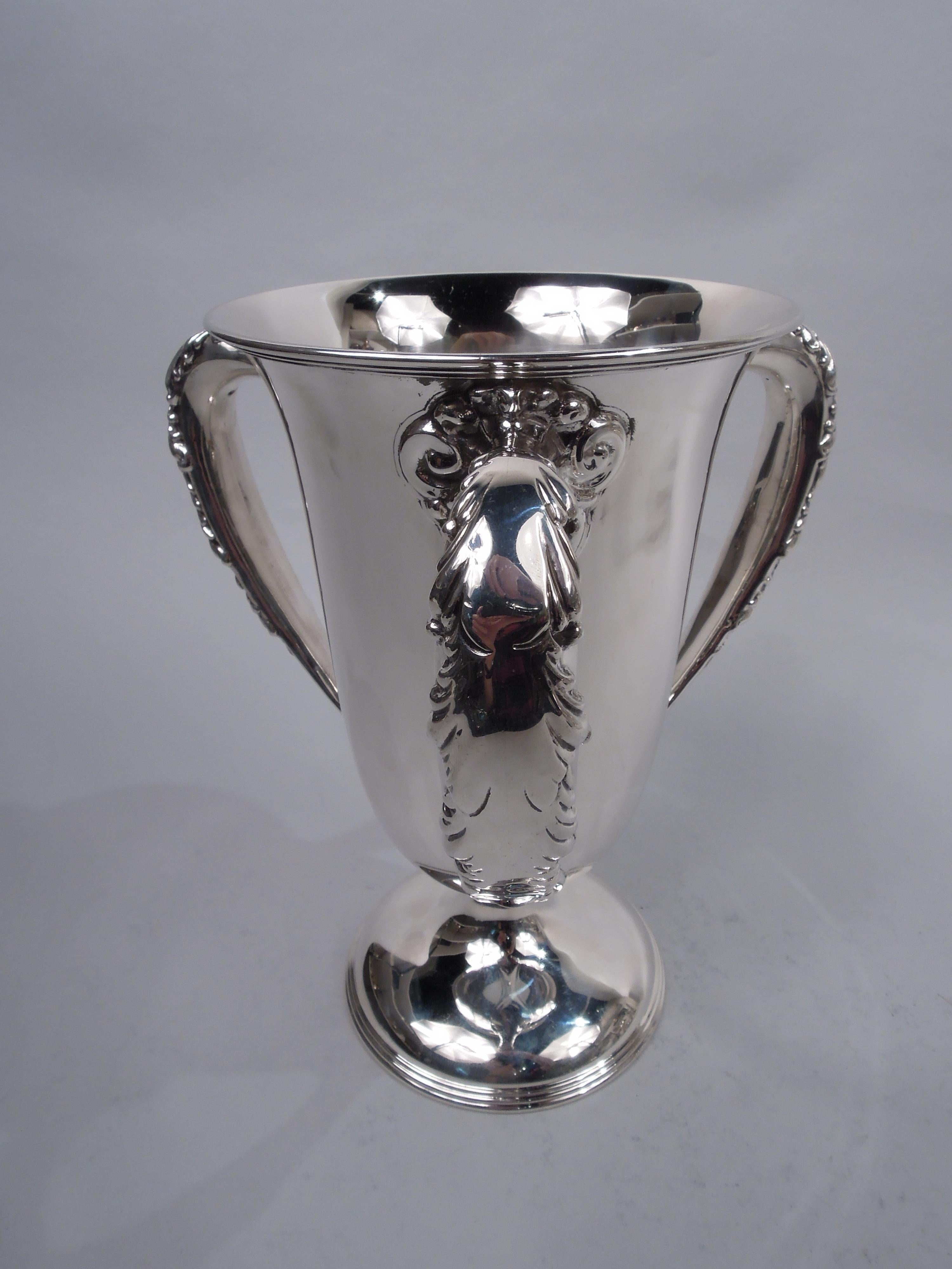 American Edwardian Classical sterling silver loving cup, ca 1910. Tapering bowl with flared rim and curved bottom on reeded domed foot; three leaf-wrapped and scroll-mounted handles. Elegant form with plenty of room for engraving. Fully marked