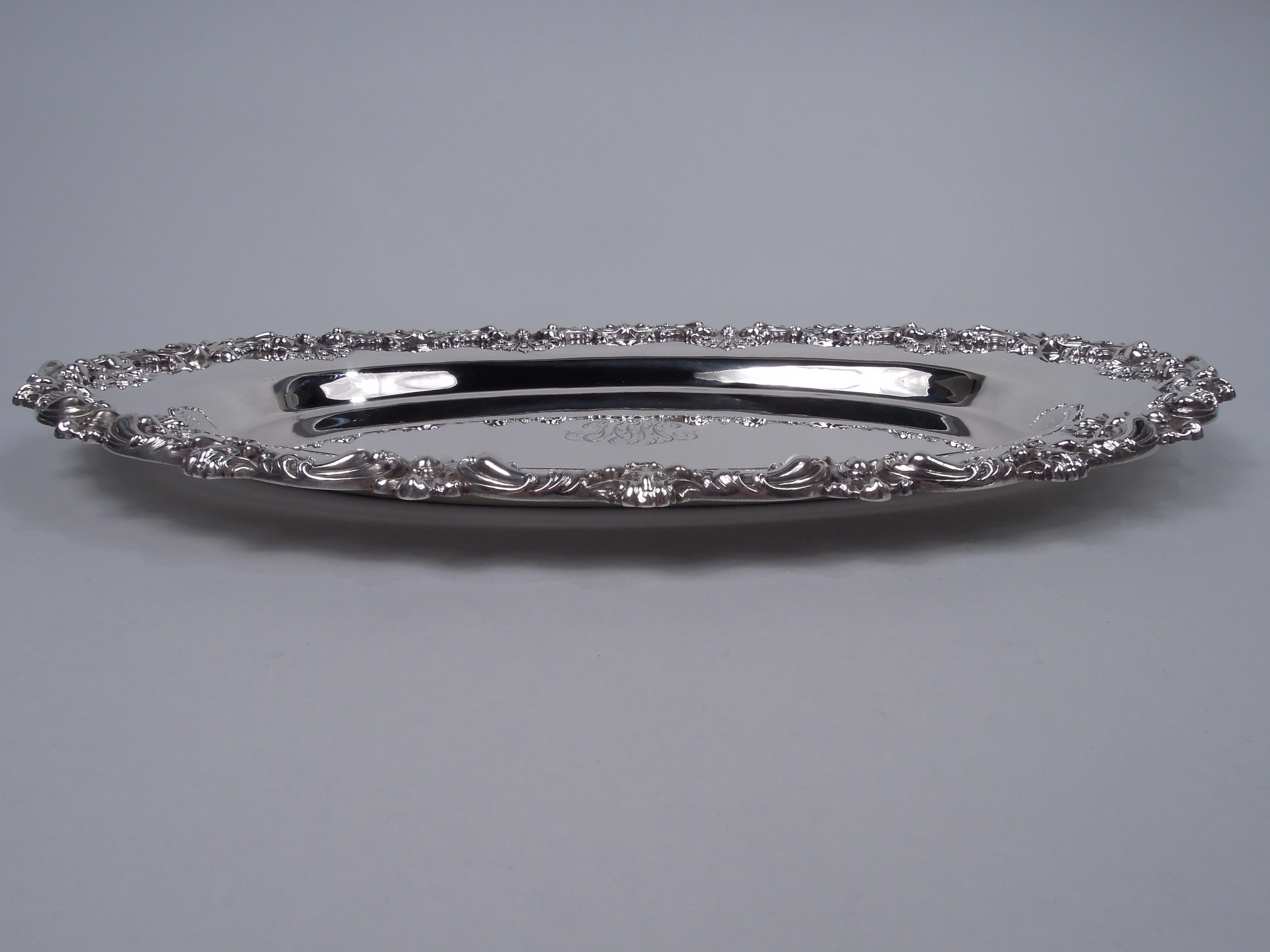 American Edwardian Classical sterling silver tray, ca 1910. Oval well engraved with wide shoulder; applied scroll and shell rim. Engraved interlaced script monogram. A capacious platter for holiday feasts. Marks include no. 4279A. No maker’s stamp