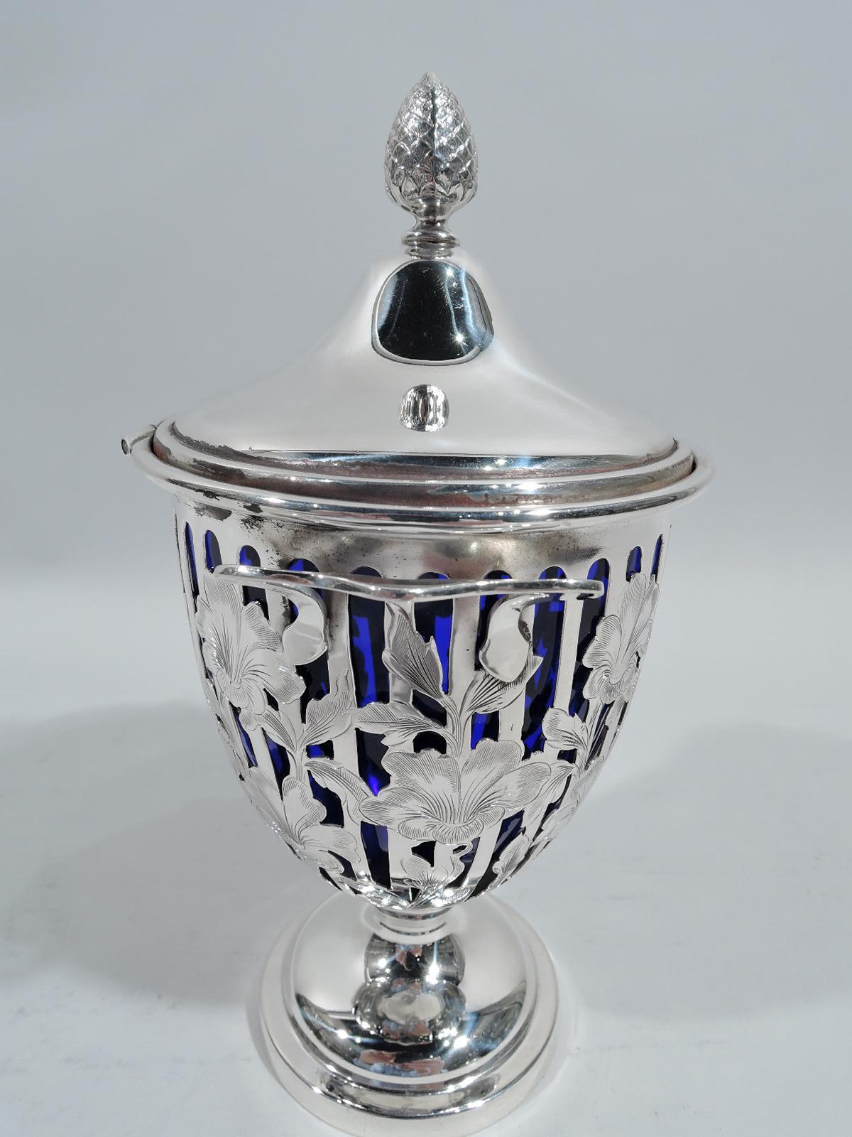 Edwardian Georgian sterling silver condiment jar. Made by George A. Henckel & Co. in New York, ca 1915. Oval bowl with vertical linear piercing overlaid with climbing and overlapping engraved flower heads. Scroll-bracket side handles, hinged and