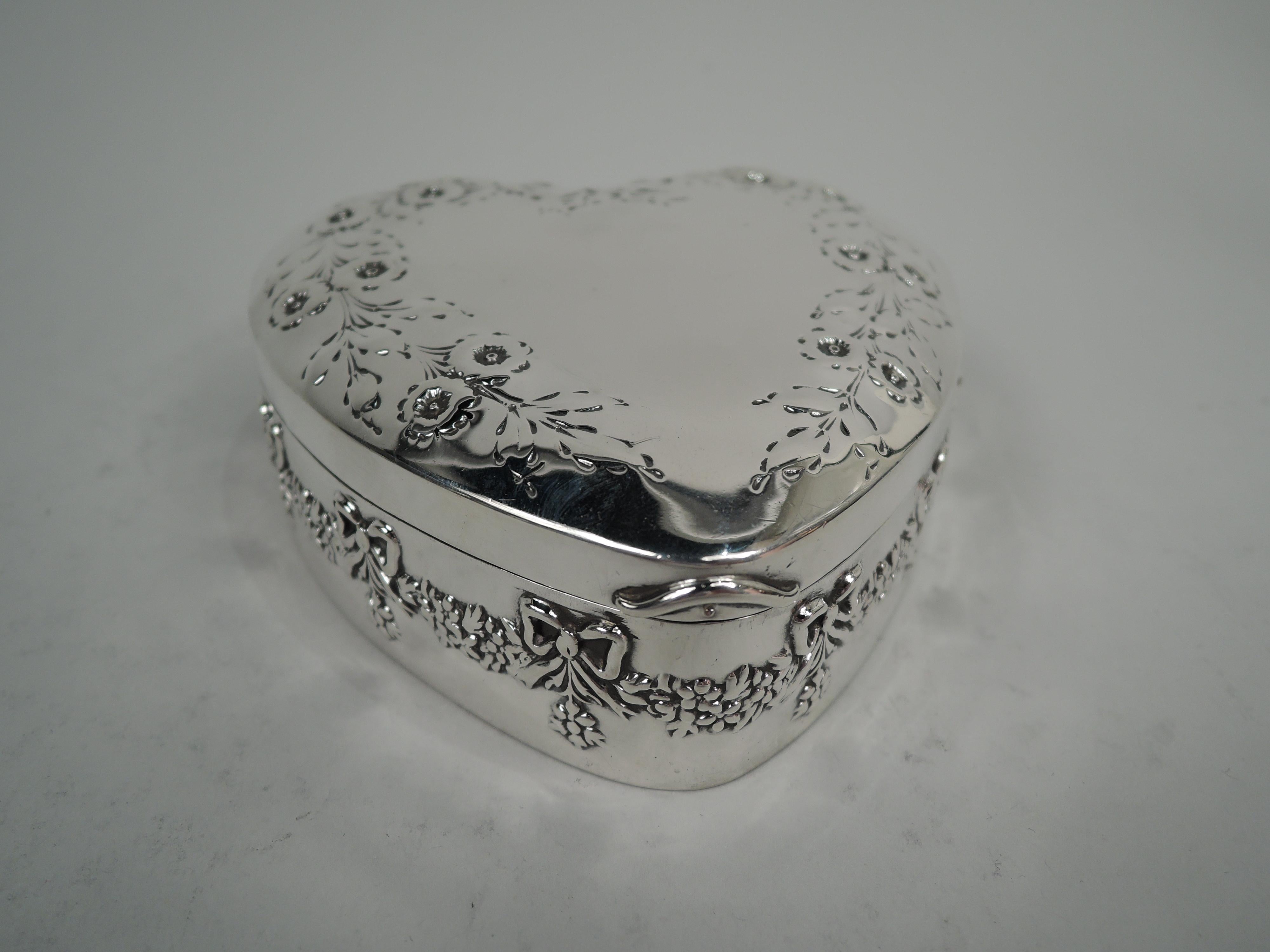 Edwardian Regency sterling silver trinket box. Made by Mauser Mfg. Co. in New York, ca 1910. Heart-shaped. Sides straight with chased garland. Cover hinged and raised with vacant center bordered by flowering branch. Gilt-washed interior. Fully