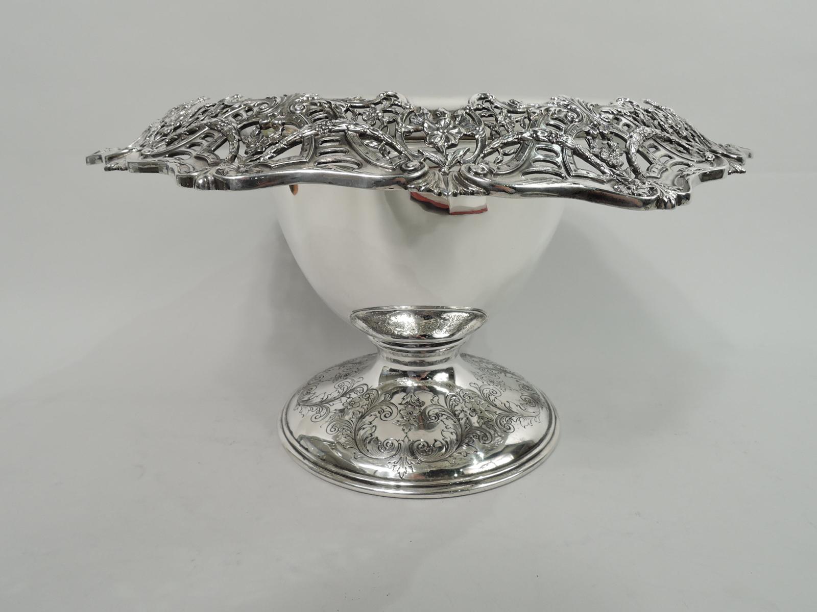 American Edwardian Regency sterling silver centerpiece bowl, ca 1910. Deep and tapering bowl, and turned-down, pierced, and scrolled rim with garlands, leaves, and flower-inset pelta shields. Foot raised with engraved leafing scrolls and flowers.