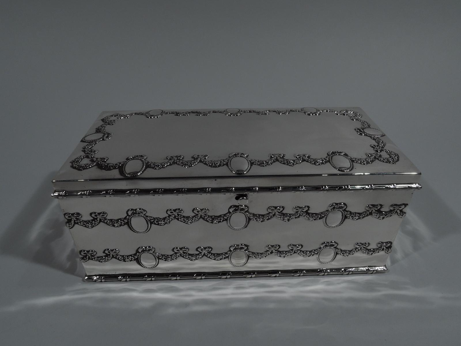 Edwardian Regency sterling silver jewelry box. Made by Durgin (part of Gorham) in Concord, New Hampshire, circa 1910. Rectangular with straight sides and hinged cover. Box encircled with double floral garland and ribbon-tied and beaded oval frames