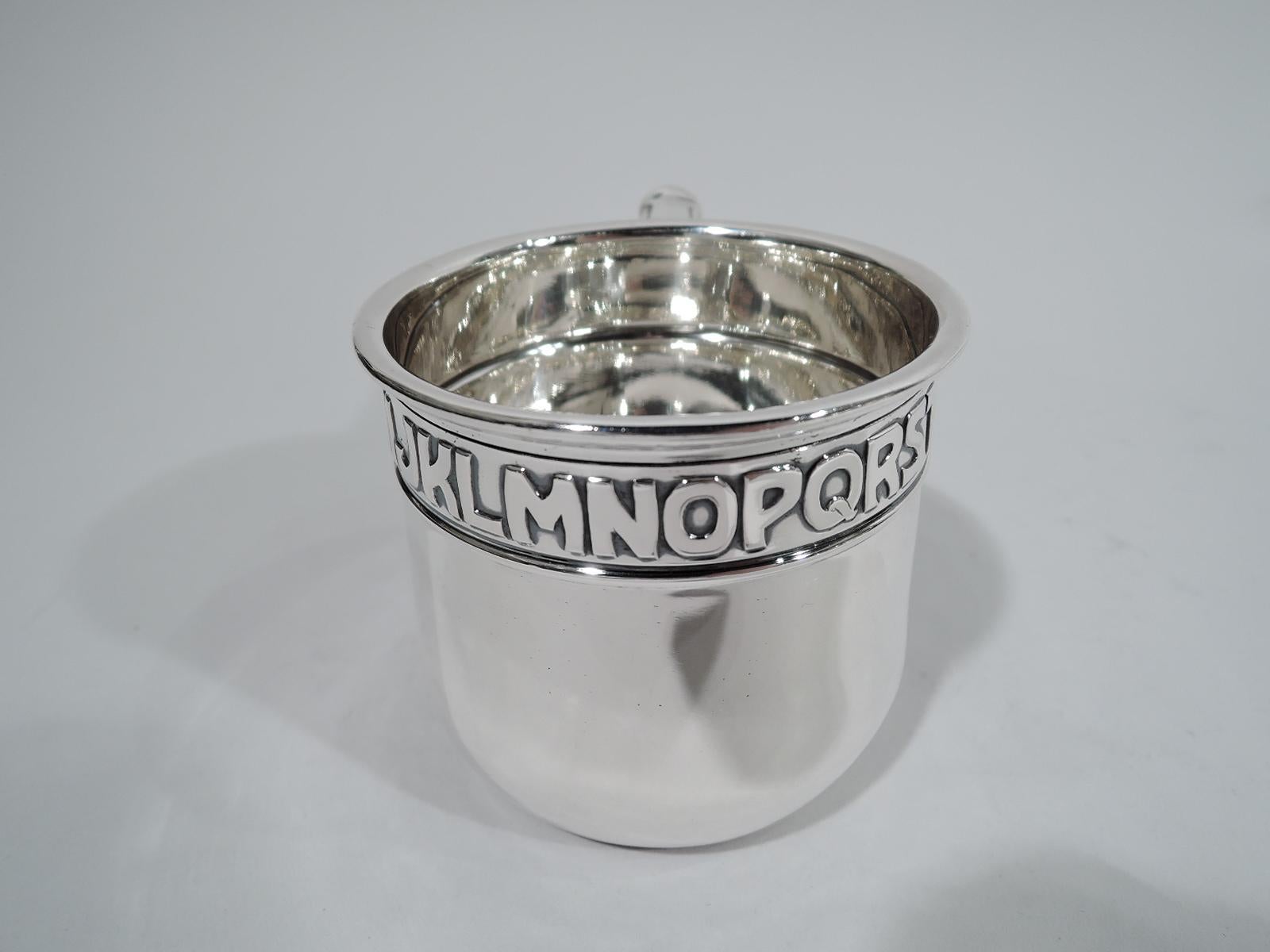 Edwardian sterling silver baby cup. Gently upward tapering sides and capped- and leaf-mounted scroll bracket handle. Acid-etched ABC border wraparound the top. All the letters in the alphabet for spelling out the name of someone extra special. Fully