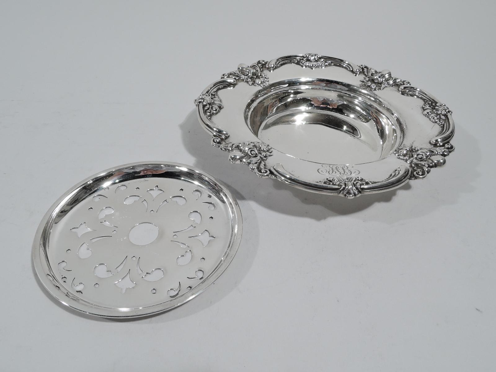 Turn-of-the-century Edwardian sterling silver butter dish. Made by Black, Starr & Frost in New York. Deep round well and Lobed rim with applied scrolls, leaves, and flowers, and engraved interlaced script monogram. Tray has ornamental piercing.
