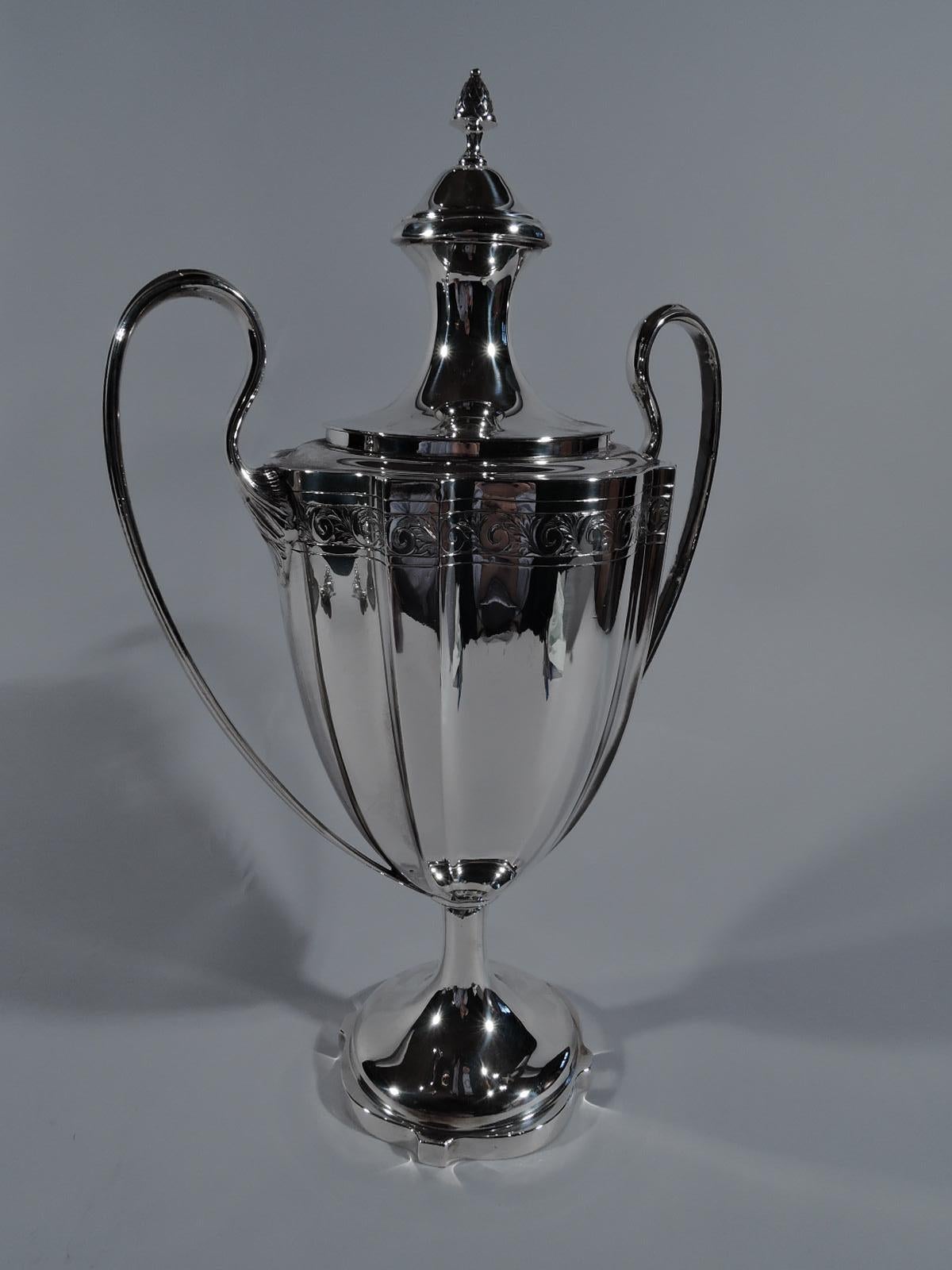 American sterling silver trophy, circa 1910. Classical amphora with curvilinear ovoid body on cylindrical stem flowing into raised foot with curvilinear rim. High-looping and leaf-mounted side handles. Double-domed cover with berry finial. Engraved