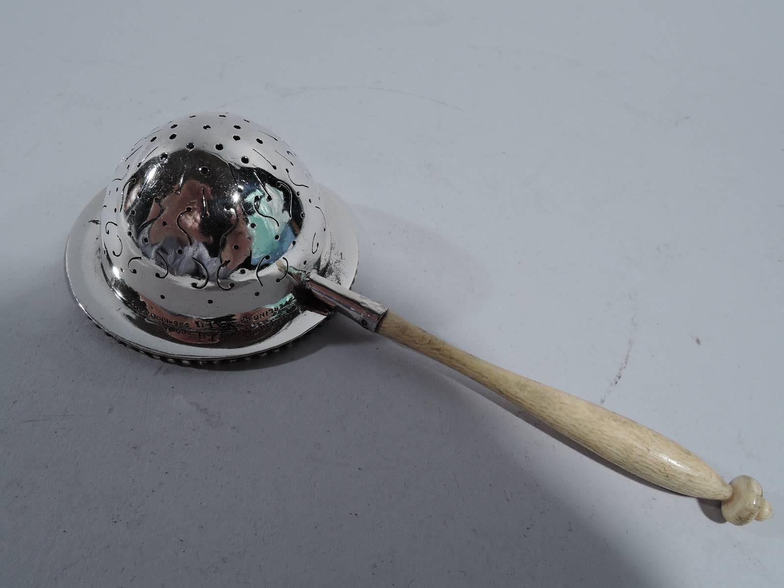 American Edwardian sterling silver tea strainer. Deep, round, and pierced bowl with wispy engraved scrolls and lines. Rim has applied beading. Baluster wood handle. Hallmarked Fradley, a New York maker. Hallmark includes no. 281U. Gross weight: 1