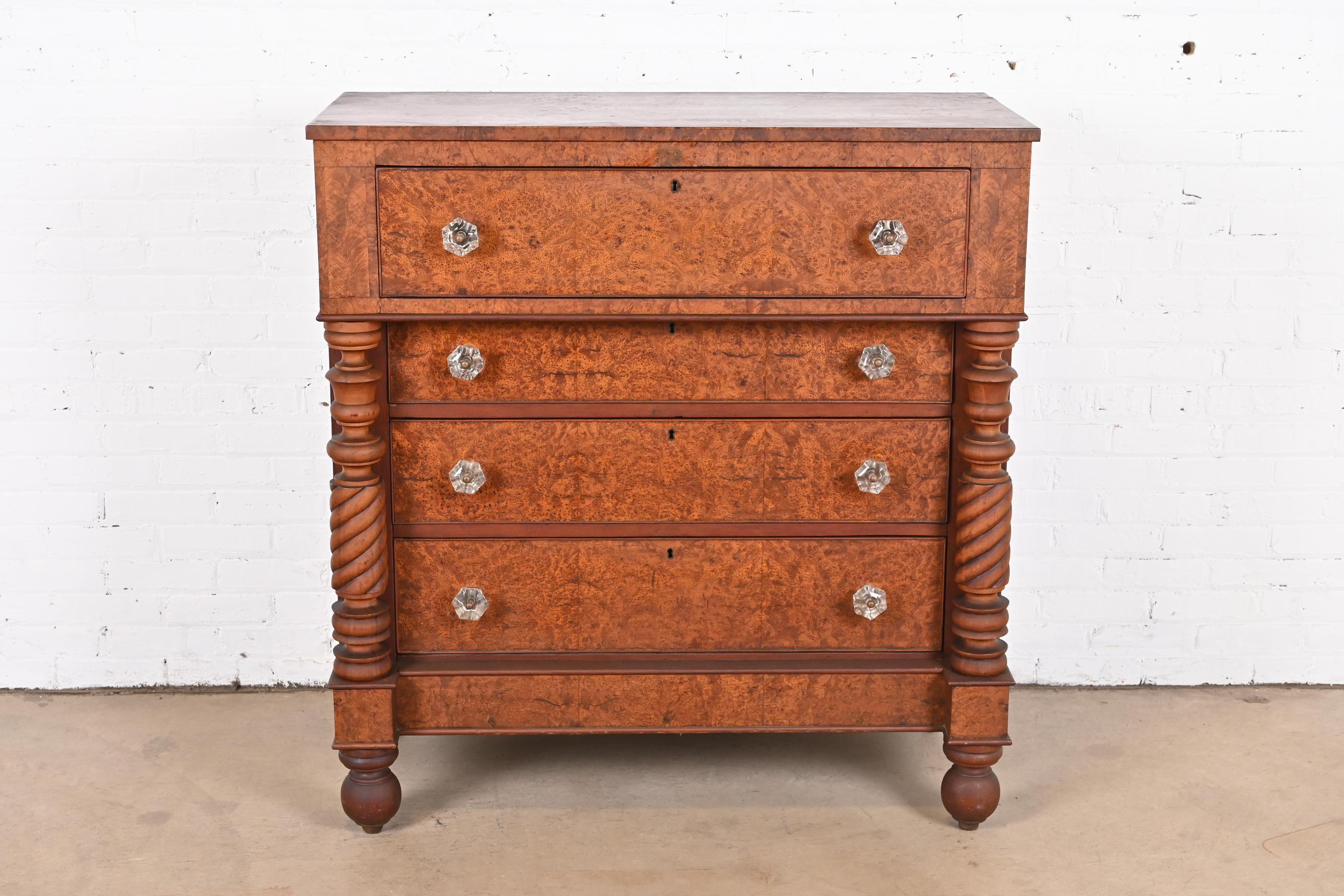 A gorgeous American Empire four-drawer highboy dresser or chest of drawers

USA, Circa 1820s

Carved cherry wood with turned columns, burled mahogany drawer fronts, and glass drawer pulls.

Measures: 43.75