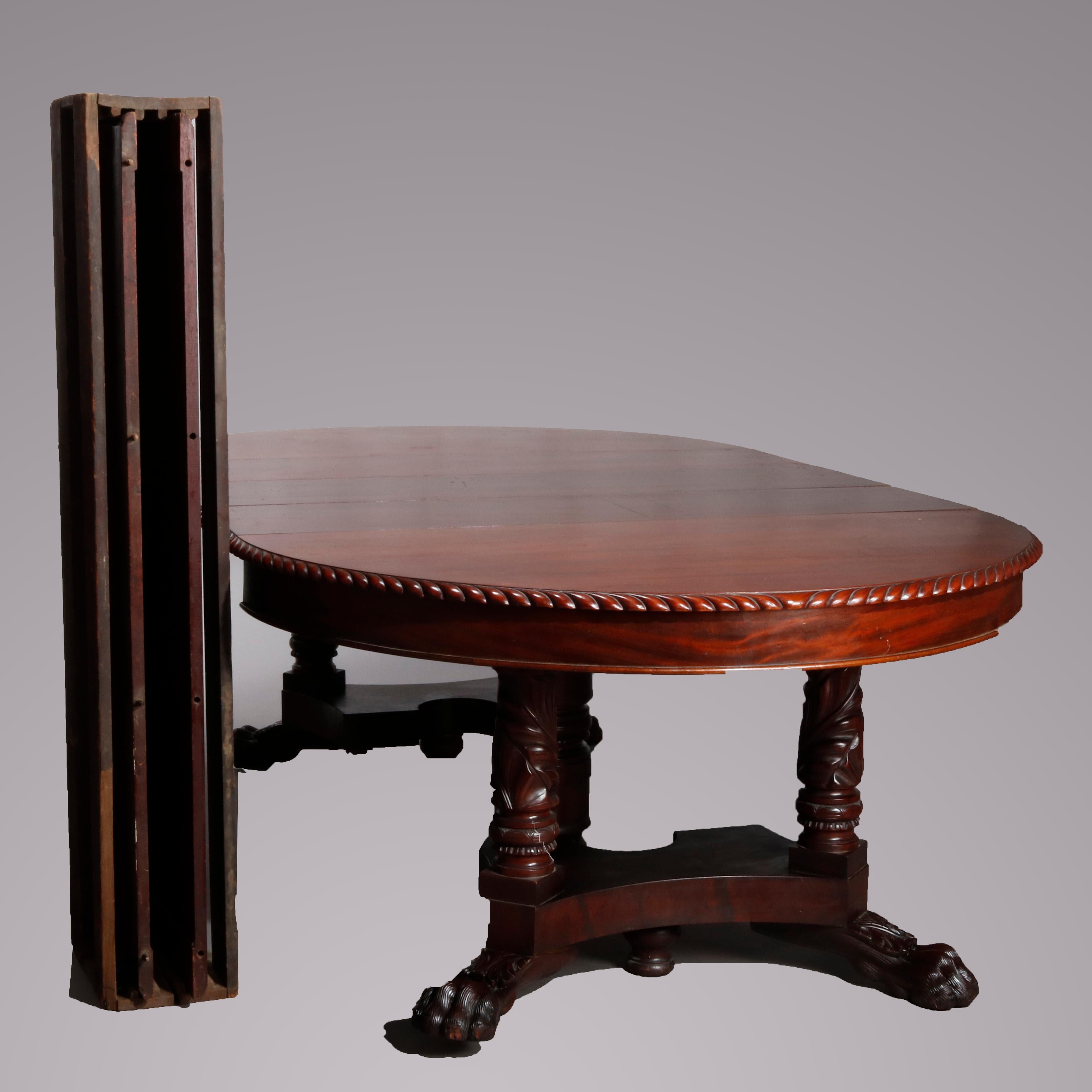 An antique American Empire extension banquet dining table offers flame mahogany construction with top having carved rope twist framing over base with foliate carved legs terminating in paw feet, includes five leaves, 19th century.

Measures: