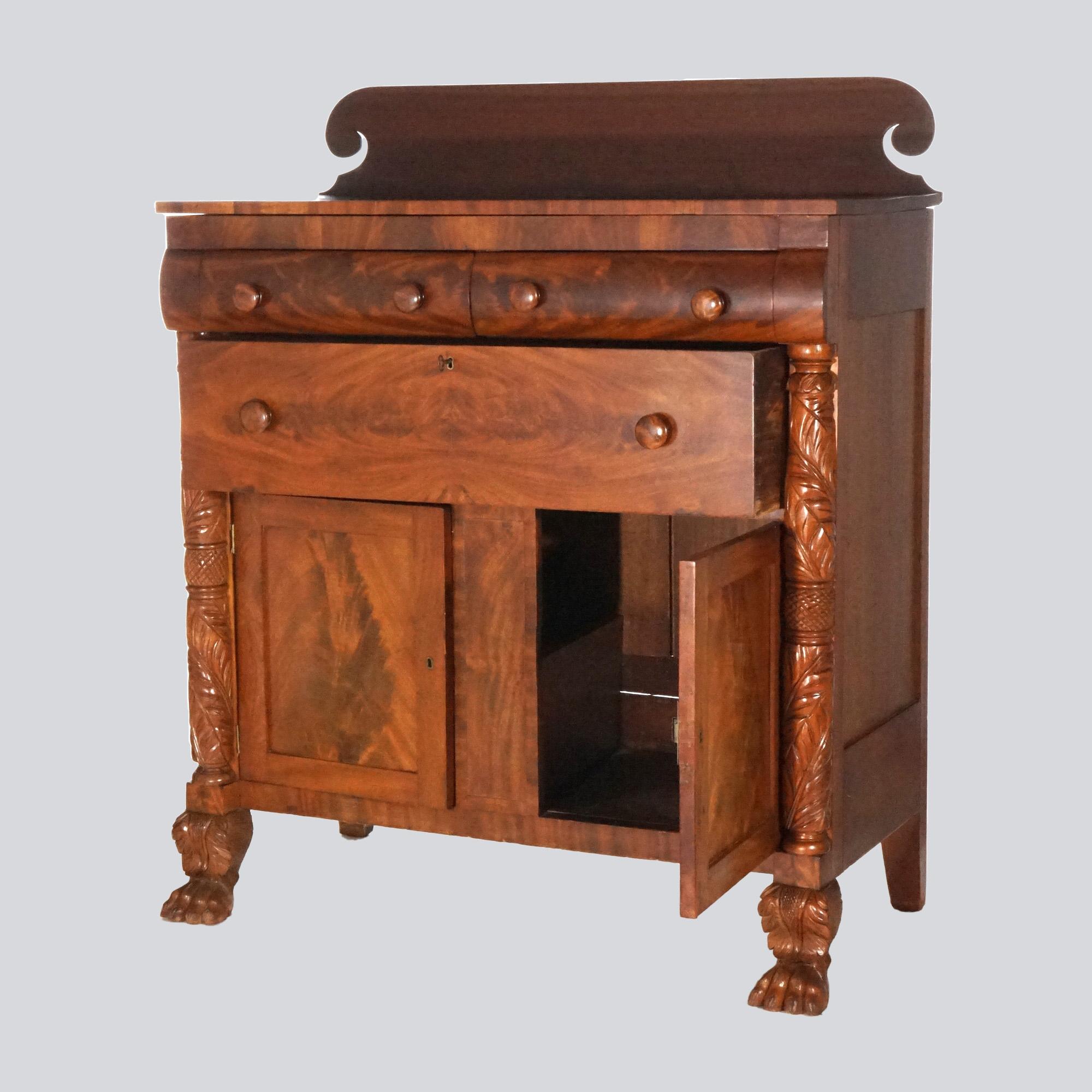 An antique Greco American Empire linen chest offers flame mahogany construction with scroll form backsplash over chest with convex drawers over long drawer and double door cabinet with flanking foliate carved columns terminating in carved paw feet,