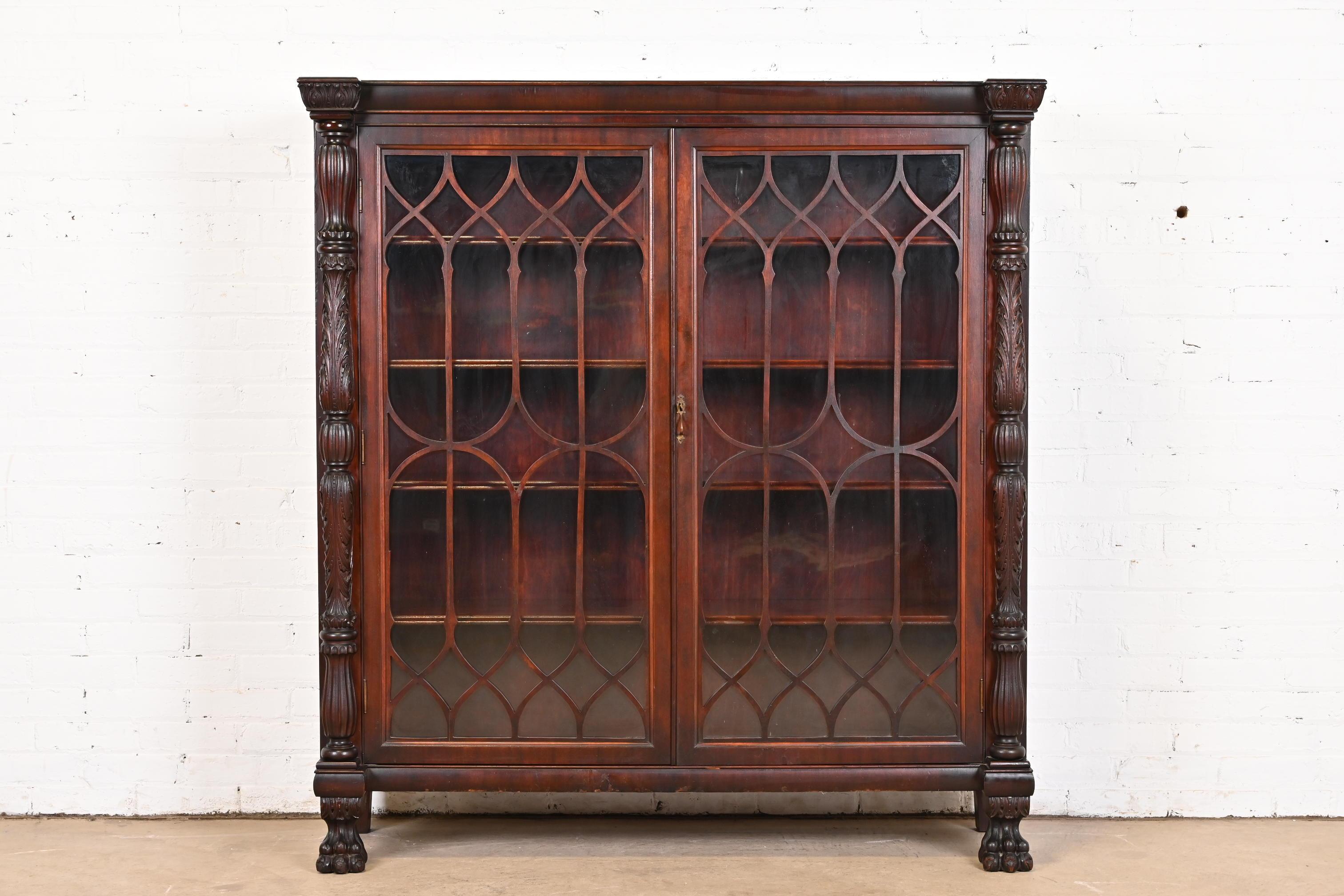 A beautiful antique American Empire or Victorian glass front bookcase with carved lion paw feet

In the manner of R.J. Horner

USA, Circa 1880s

Carved mahogany, with mullioned glass front doors, and original brass hardware. Cabinet locks, and key