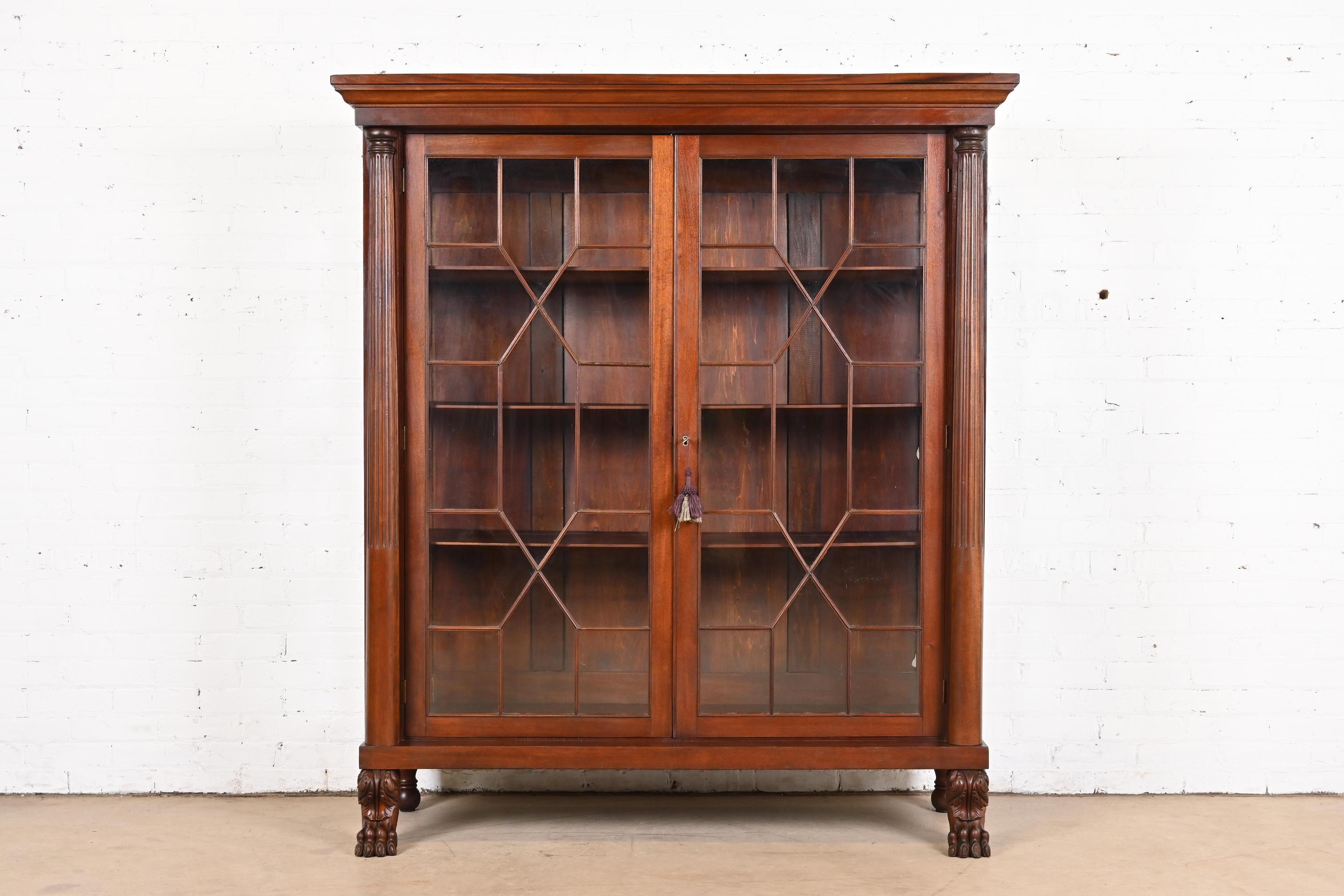 A beautiful antique American Empire or Victorian glass front bookcase with carved columns and lion paw feet

In the manner of R.J. Horner

USA, Circa 1890s

Carved mahogany, with mullioned glass front doors and sides. Cabinet locks, and key is