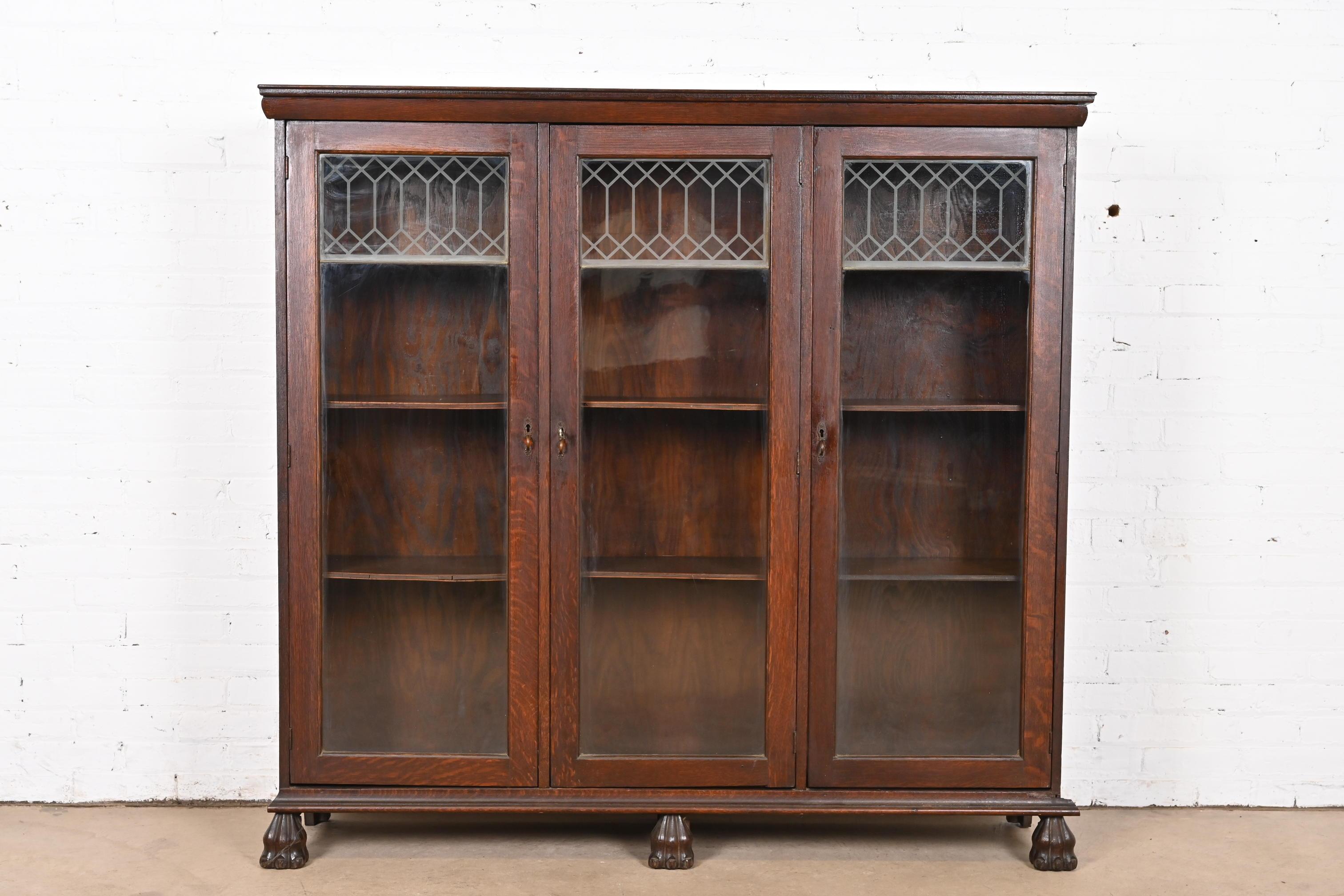 An outstanding antique American Empire or Victorian triple bookcase cabinet 

In the manner of R.J. Horner

USA, Circa 1890s

Gorgeous quarter sawn oak, with lion paw feet, glass front doors with faux leaded glass panels, and original brass