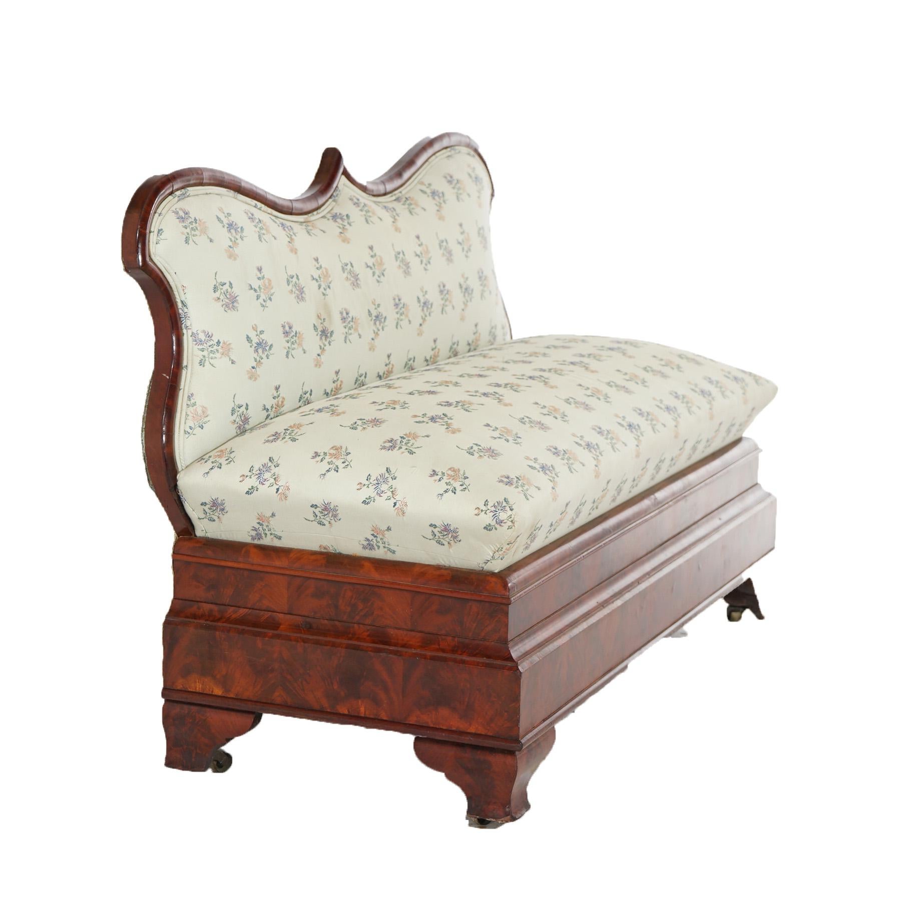 An antique American Empire Classical Greco slipper bench offers flame mahogany frame with shaped back with upholstered back and bench over ogee base raised on bracket feet, c1840

Measures- 32.25''H x 48''W x 20.75''D