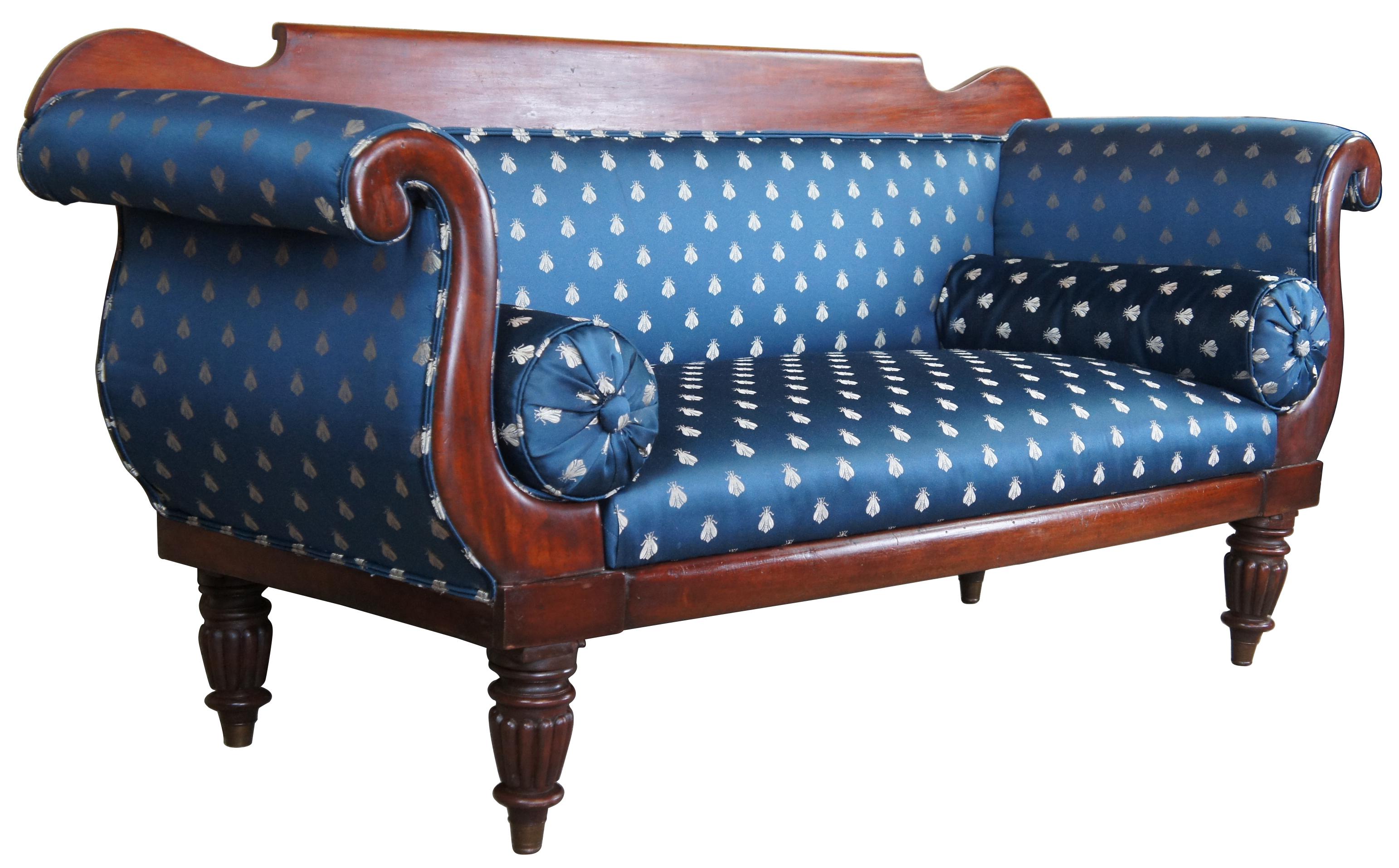 Antique Victorian parlor settee or sofa. Made of mahogany featuring rolled arms and blue silk scalamandre upholstery with insects and bolster pillows. The sofa is supported by turned reeded legs with brass caps.
    