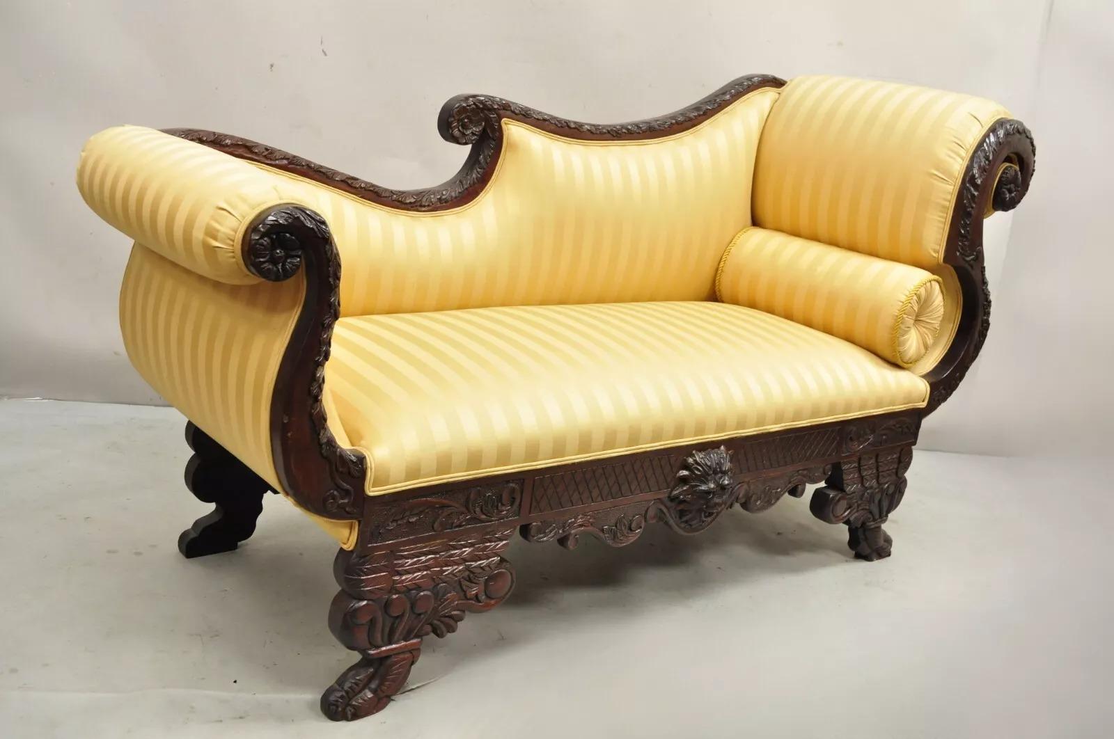 Antique American Empire Figural Carved Mahogany Recamier Gold Chaise Lounge Sofa. Item features a carved face to lower crest ands further carved wooden frame throughout raised on paw feet and upholstered in a stunning gold striped fabric. Circa Late