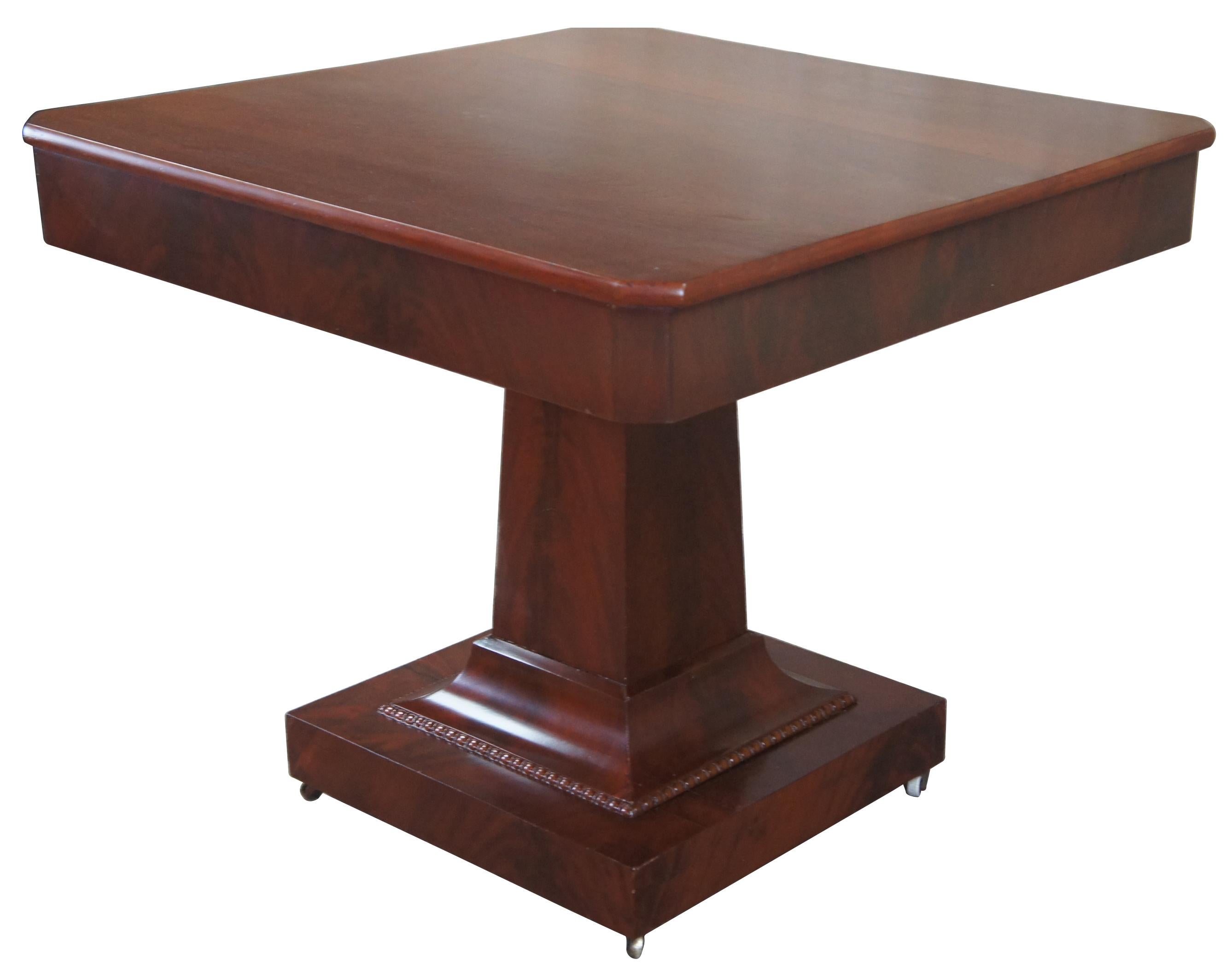 Antique American Empire pedestal center table. Made of mahogany with a crotch veneer featuring a square form and pedestal base with castors. Measures: 34