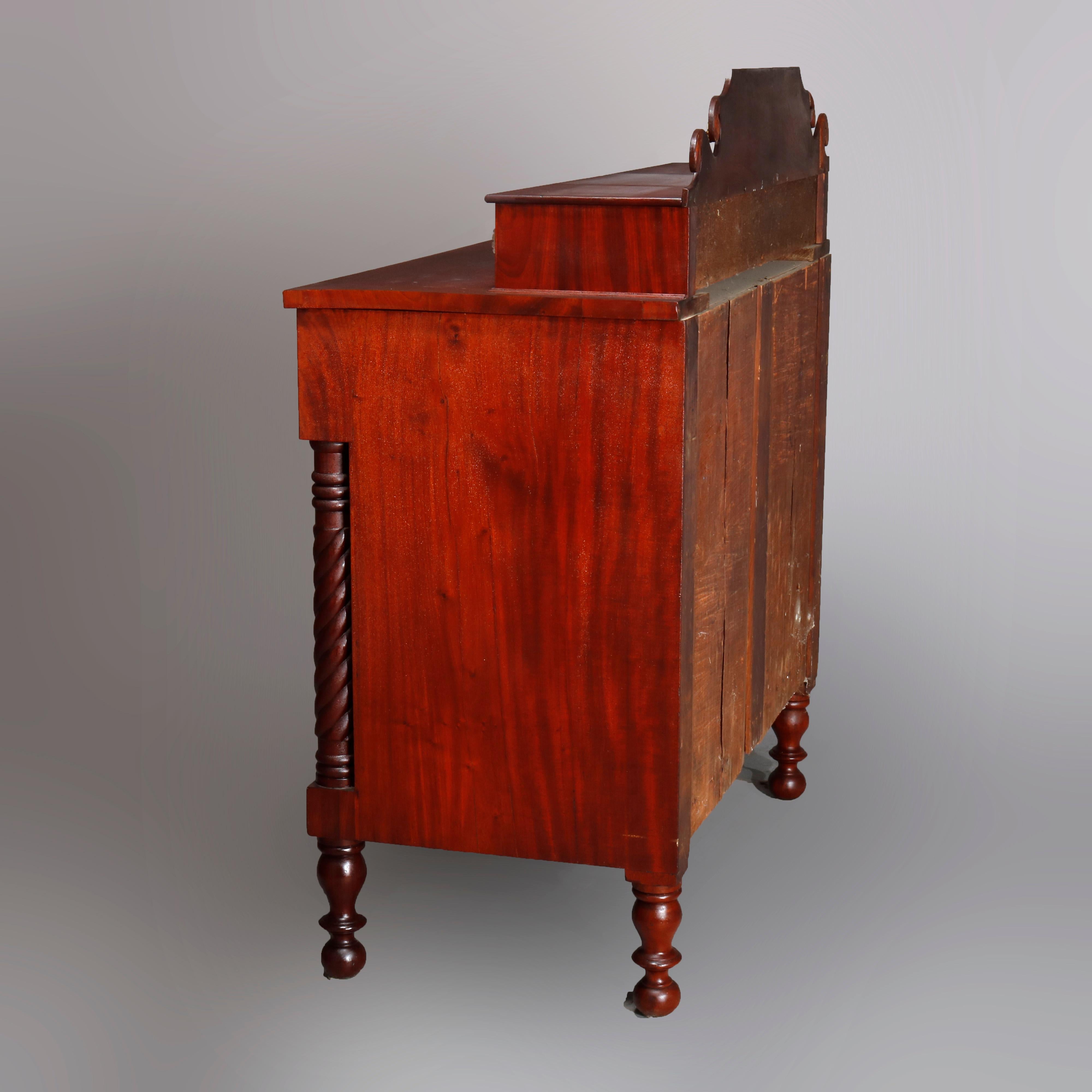 An antique American Empire chest of drawers offers flame mahogany construction with scrolled backsplash over case with three glove drawers, one oversized frieze drawer and three long drawers flanked by full twisted rope column supports, raised on