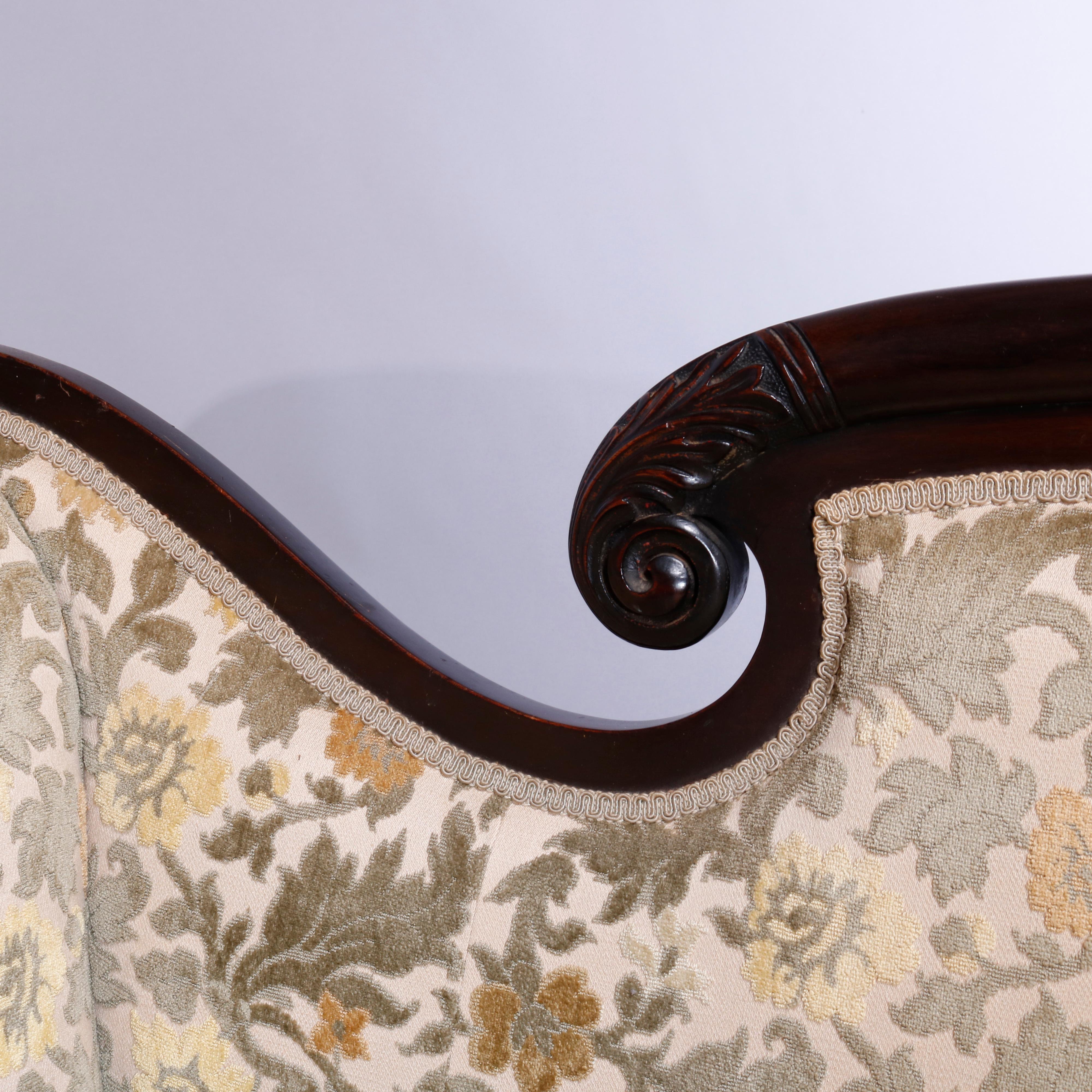 An antique American Empire Federal style sofa offers flame mahogany frame with scroll form rail and arms having carved acanthus over upholstered back and seat, raised on carved paw feet, c1840

Measures: 35