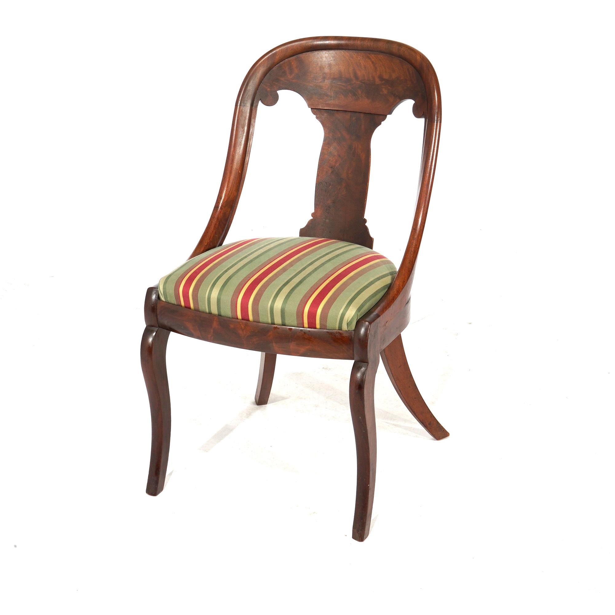 An antique set of four American Empire dining chairs offer flame mahogany construction in gondola form with slat backs over upholstered seats and raised on saber legs, c1840

Measures- 32.5''H x 17.75''W x 21''D.

Catalogue Note: Ask about