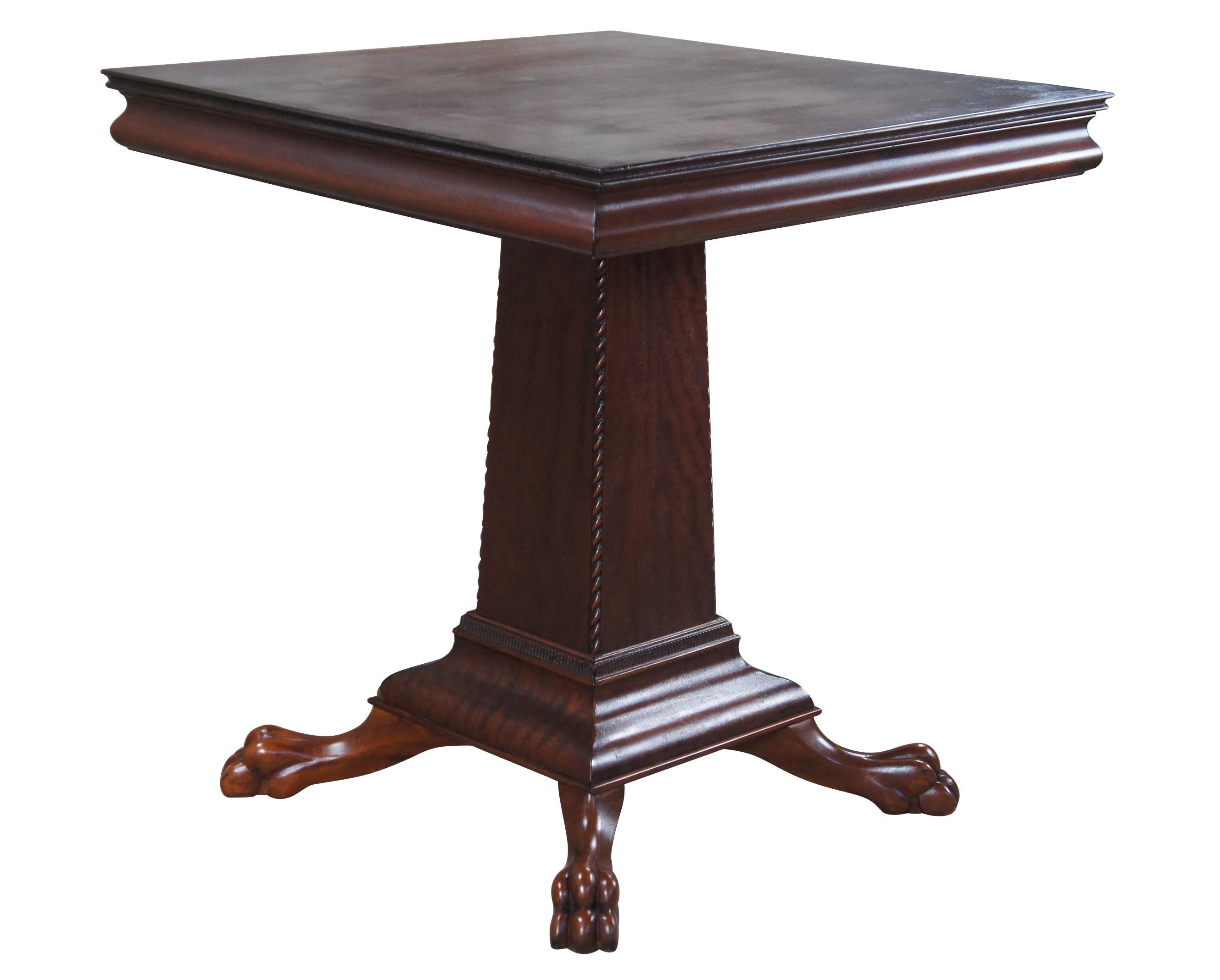 Antique American Empire mahogany game table featuring square form with a tapered pedestal, large carved claw feet, serpentine edge and twisted / fluted accents.