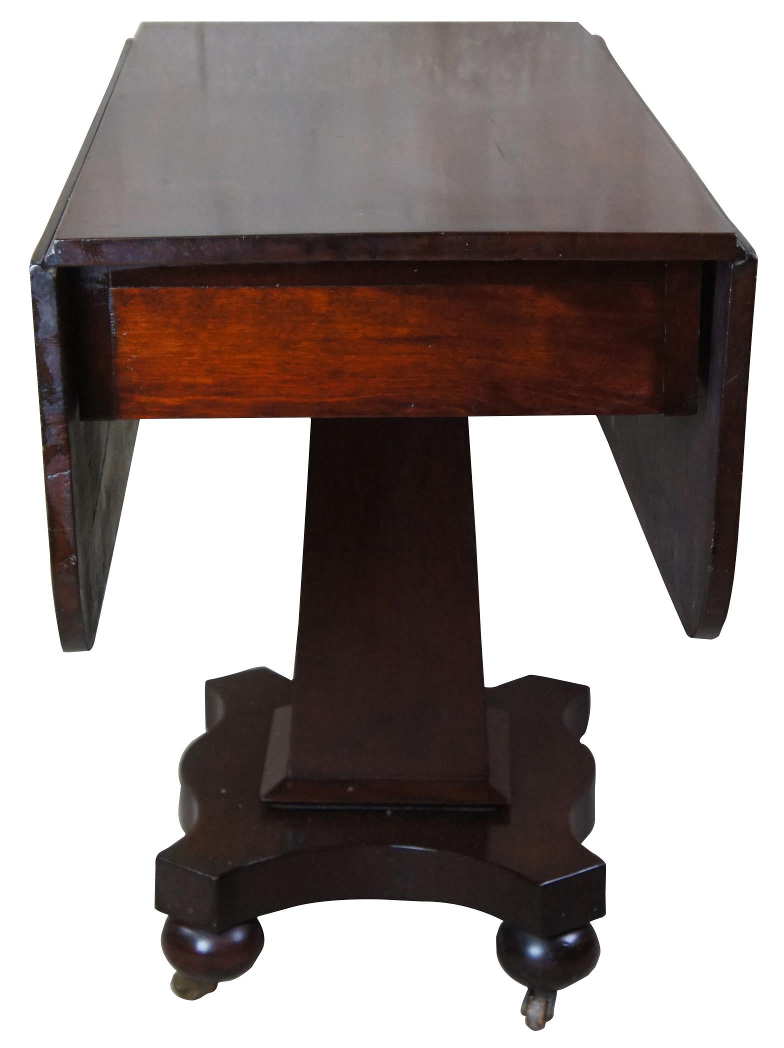 American Empire drop-leaf table, circa 1850s. Made from mahogany with square tapered pedestal and serpentine base with bun feet.
 