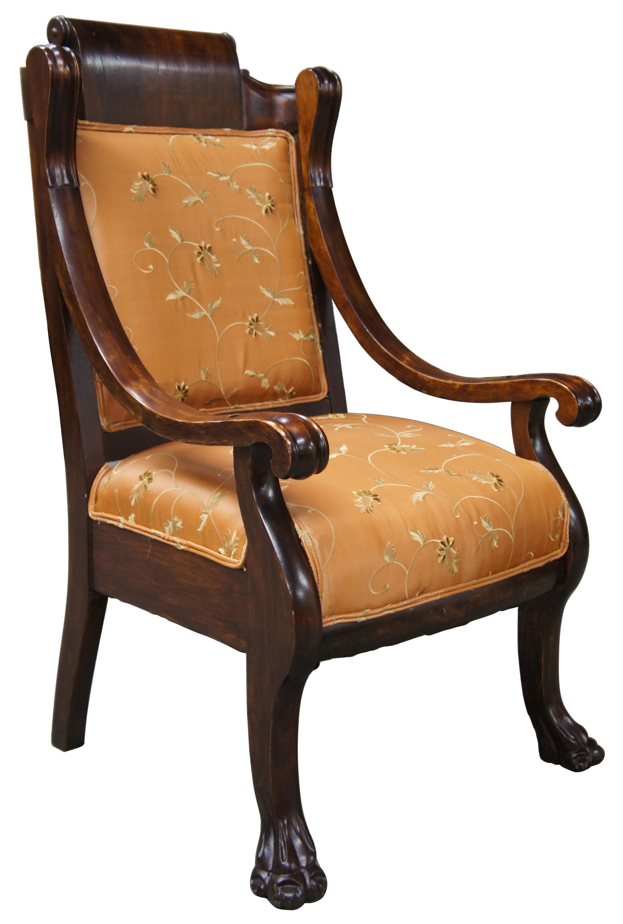 Victorian era parlor armchair drawing inspiration from American Empire styling. Made from mahogany with sloped arms over a peach silk floral upholstery. Chair rests upon paw feet, castors could be added.

 