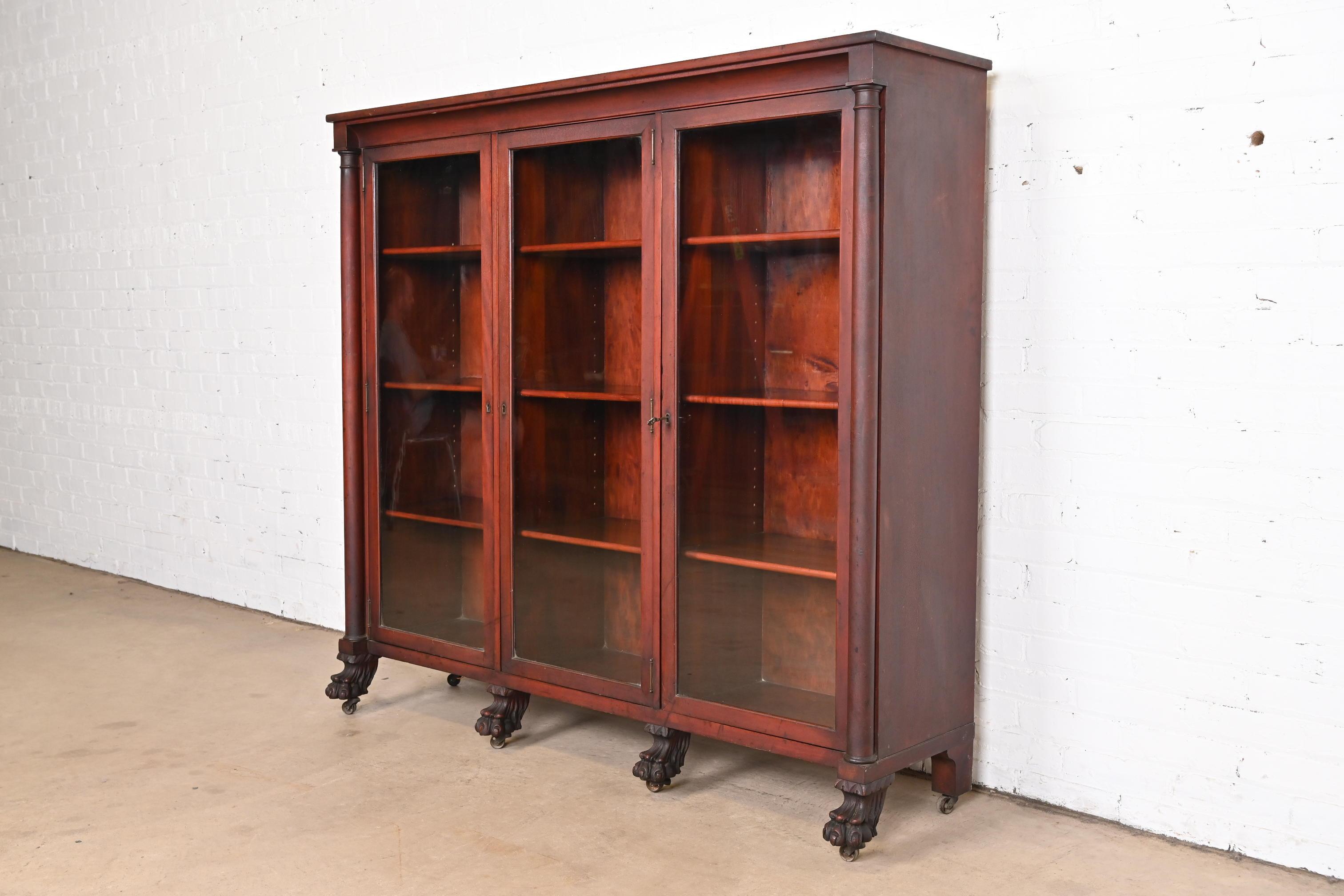 A beautiful antique American Empire or Victorian glass front triple bookcase with carved lion paw feet

In the manner of R.J. Horner

USA, circa 1890s

Carved mahogany, with glass front doors. Cabinets lock, and key is included.

Measures:
